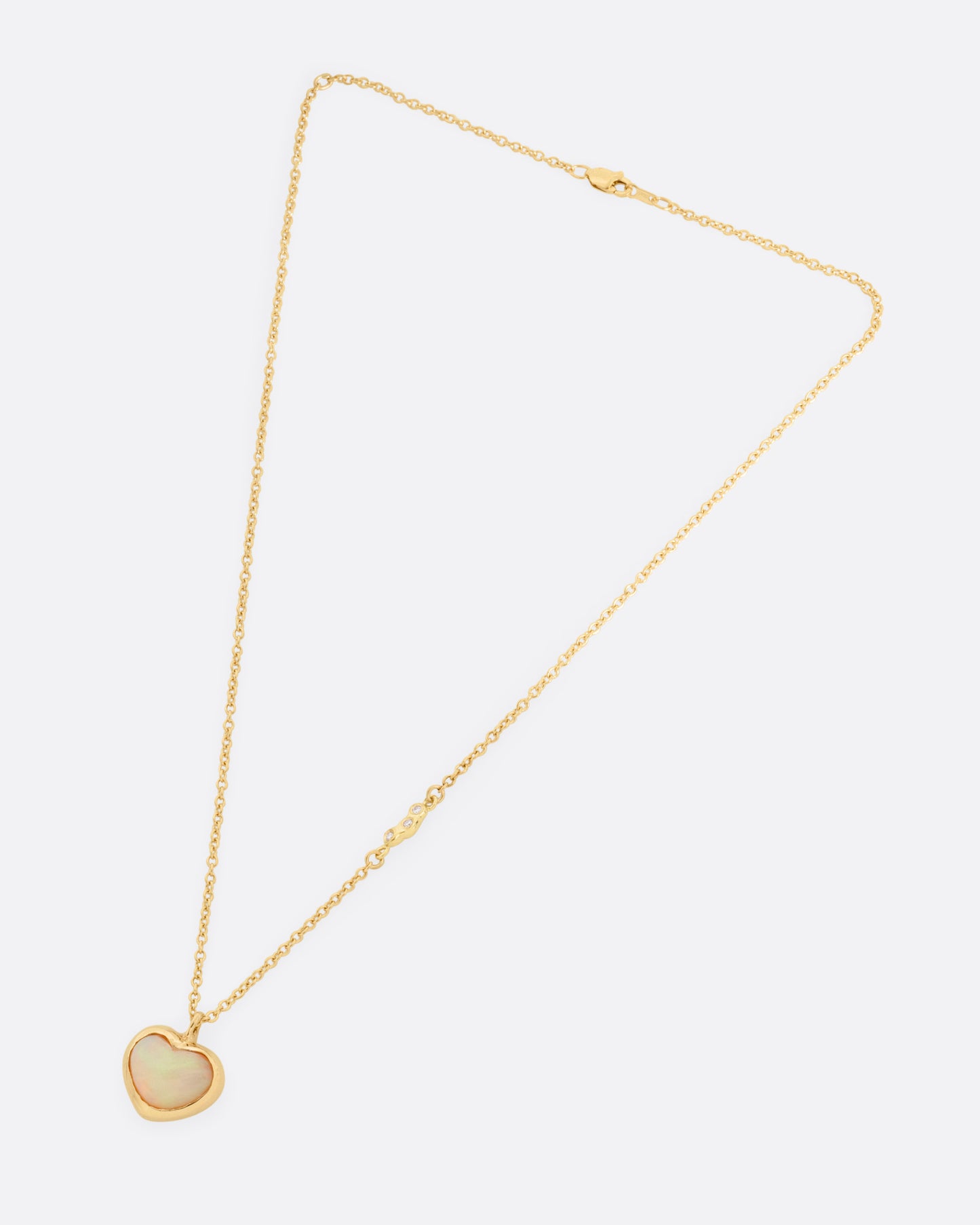 A yellow gold cable chain necklace with a large dimensional opal heart pendant, shown from the front.