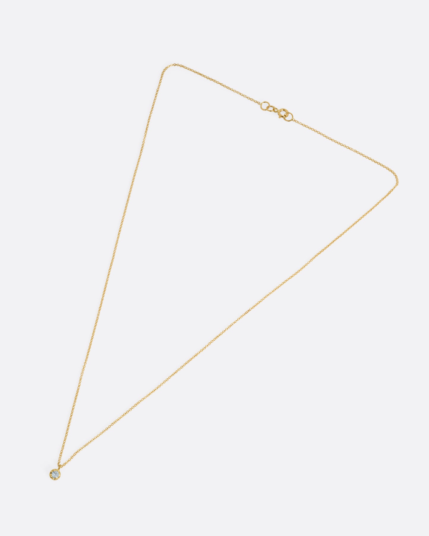 A yellow gold cable chain necklace with a prong set aquamarine, shown from the front.