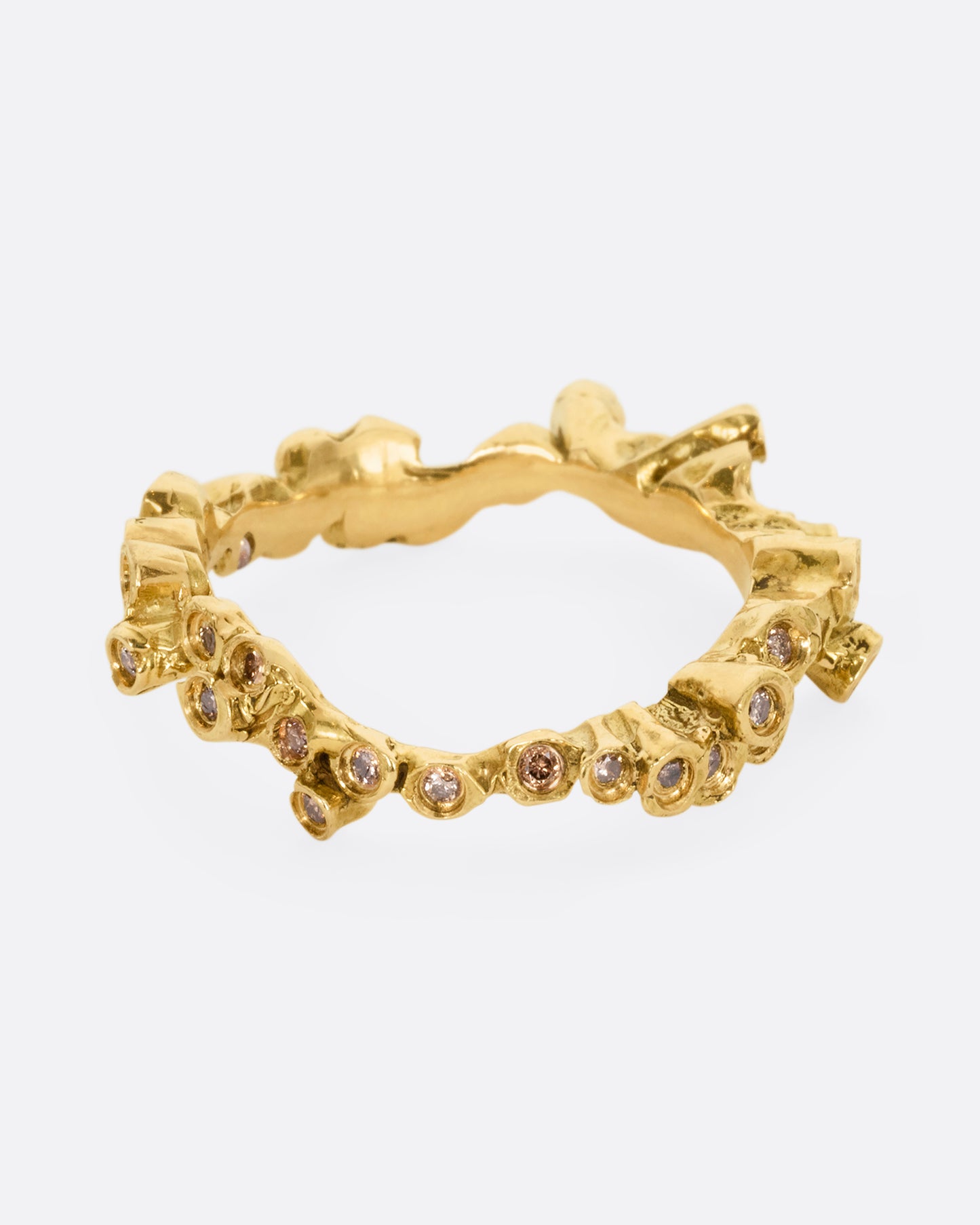 A yellow gold ring with cognac diamonds in protruding bezel settings that wrap around the entire band. Shown from the front.