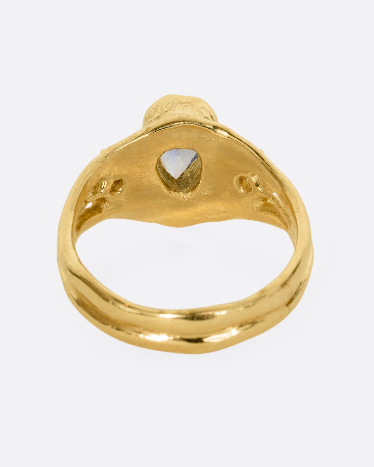 A yellow gold ring with a blue kite shaped sapphire and two yellow sapphires. Shown from the back.