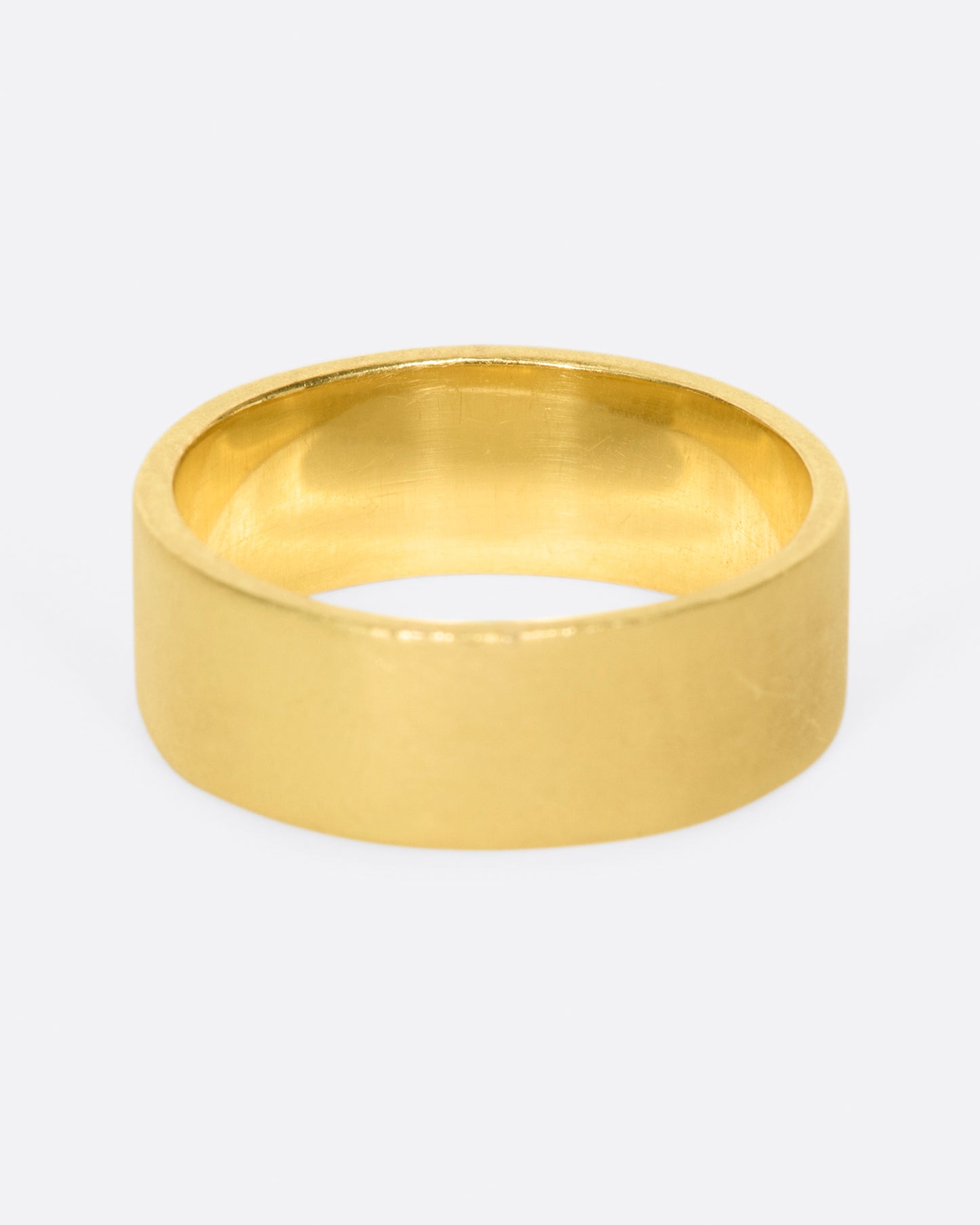 A yellow gold band with 15 grey diamonds in three rows of five at the center. Shown from the back.