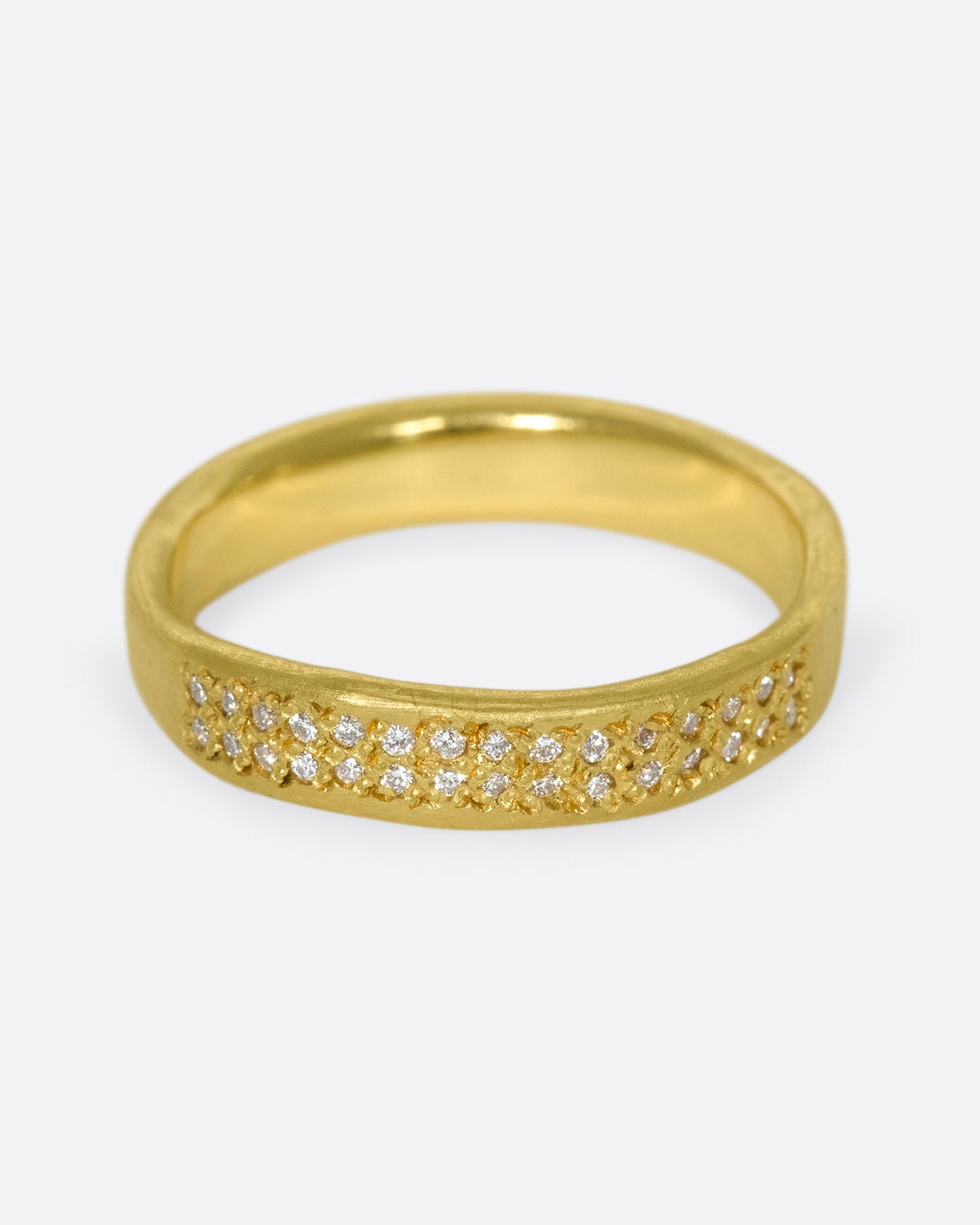 A hand-formed, brushed gold band with two rows of diamonds along half of it. Shown from the front.