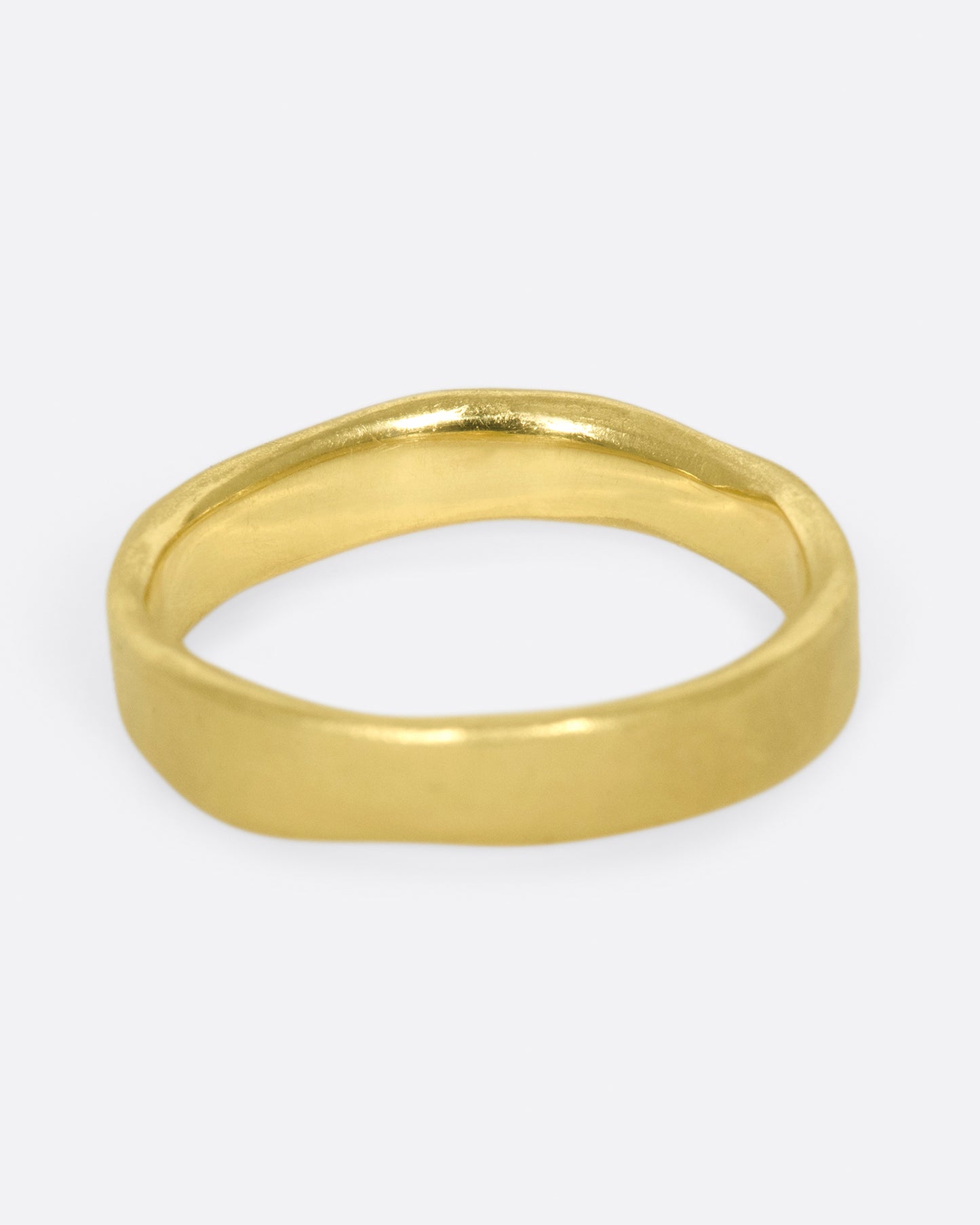 A hand-formed, brushed gold band with two rows of diamonds along half of it. Shown from the back.
