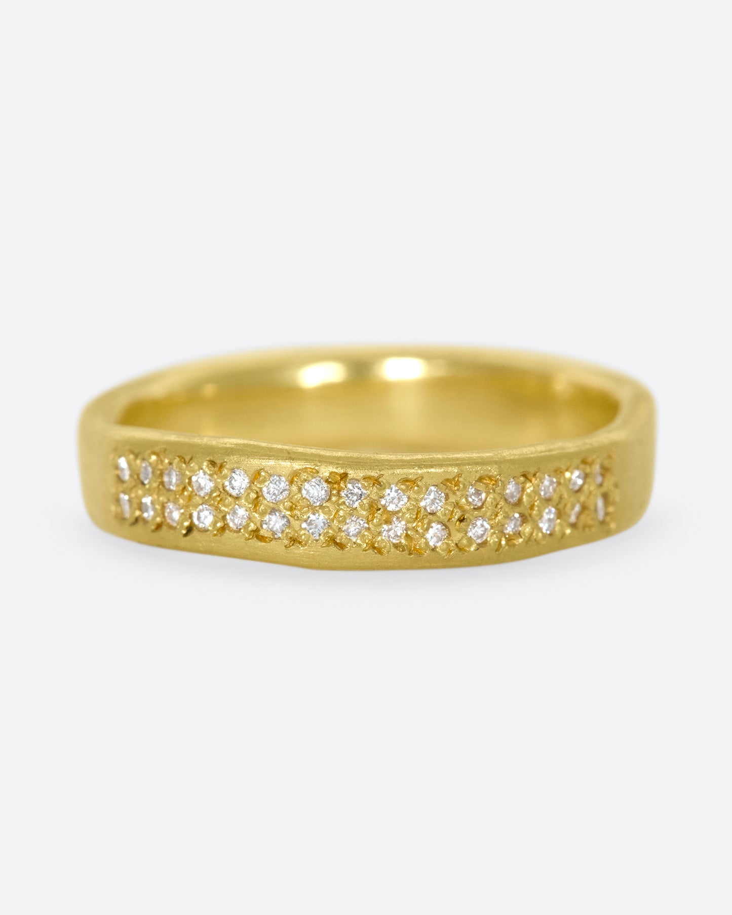 A hand-formed, brushed gold band with two rows of diamonds along half of it. Shown from the front.