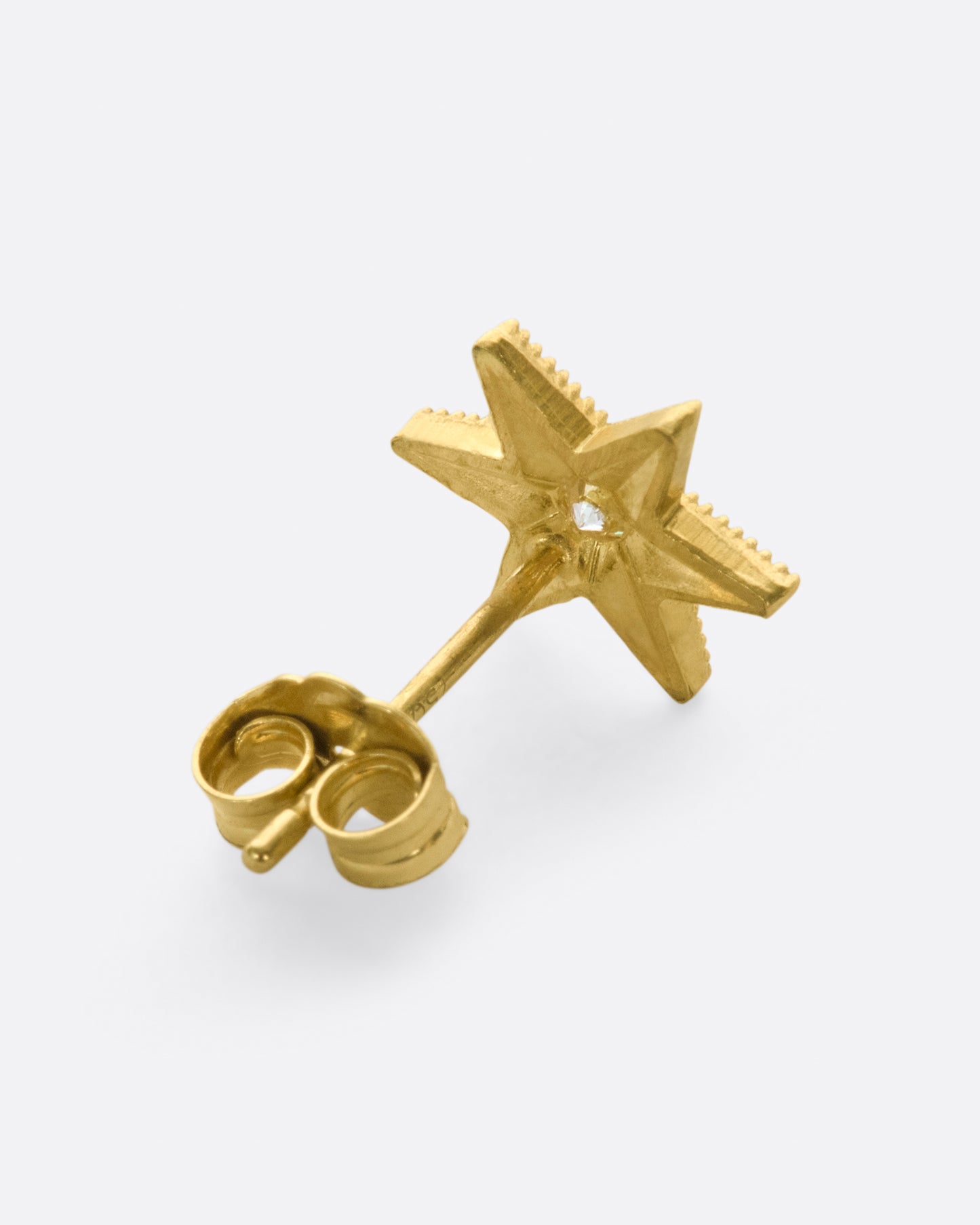 A yellow gold star stud earring with a central diamond and six points with millgrain details.Shown from the back.