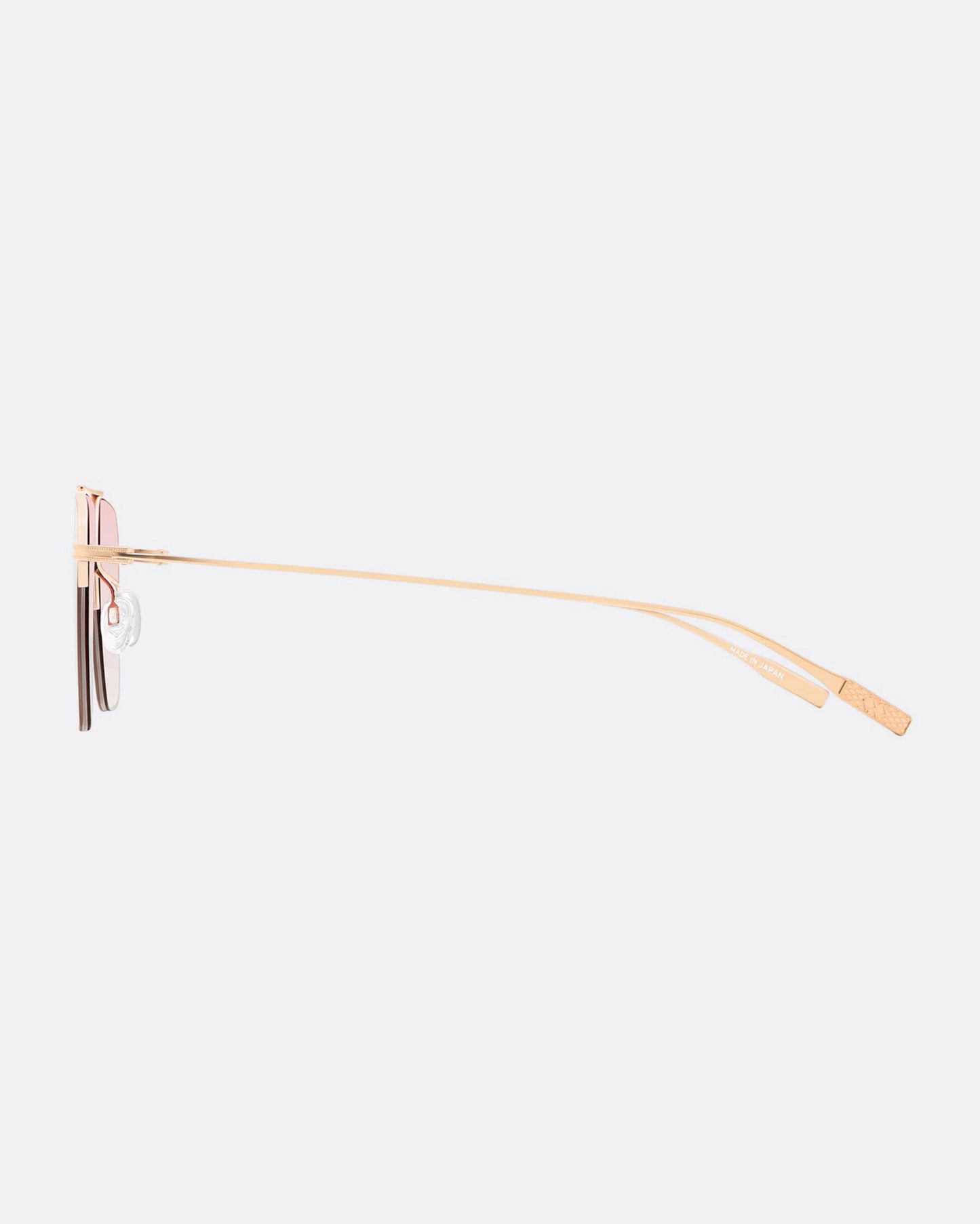 A pair of navigator sunglasses with pink gradient lenses. Shown from the side.