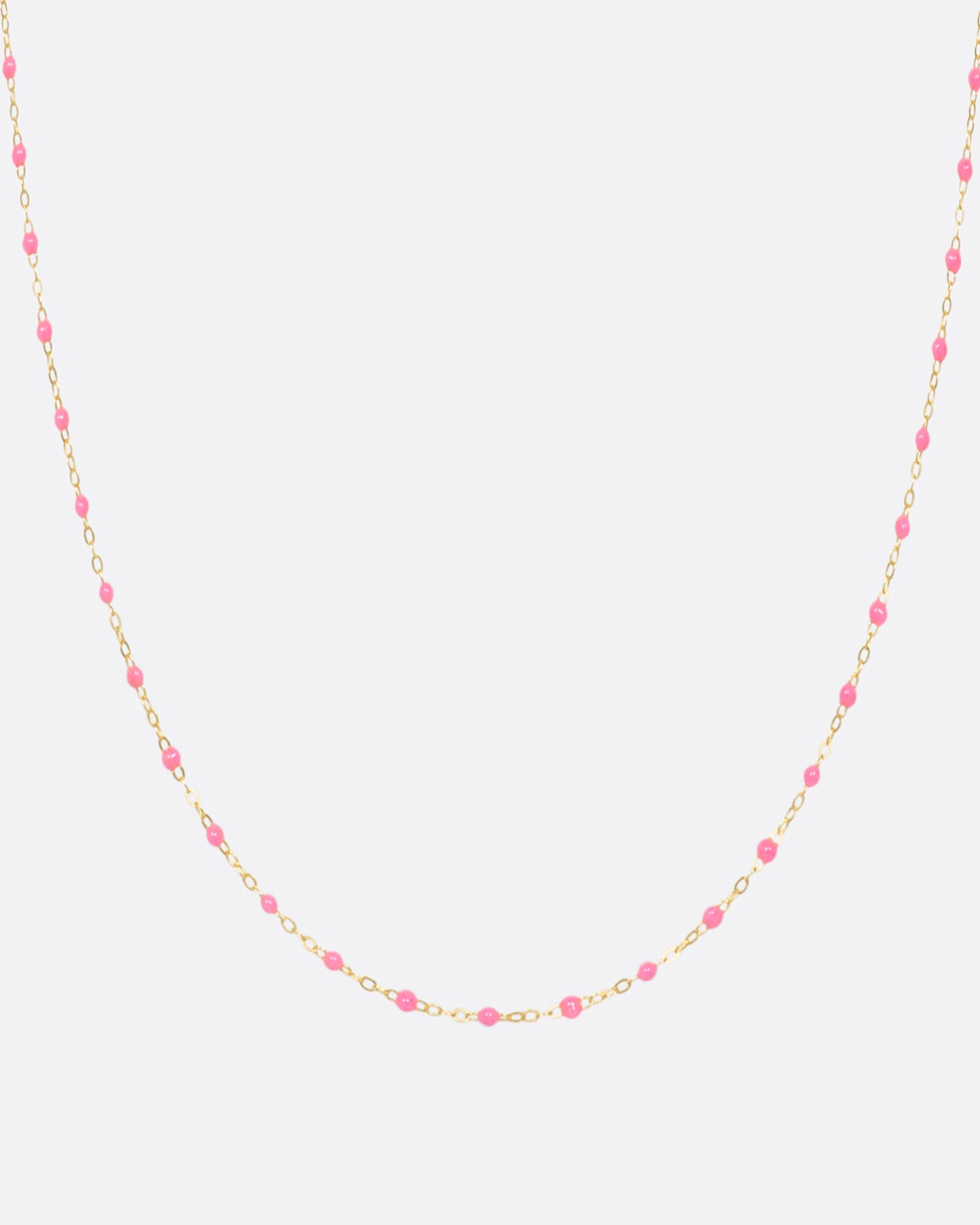 A yellow gold cable chain necklace with droplets of pink resin. Shown from the front.
