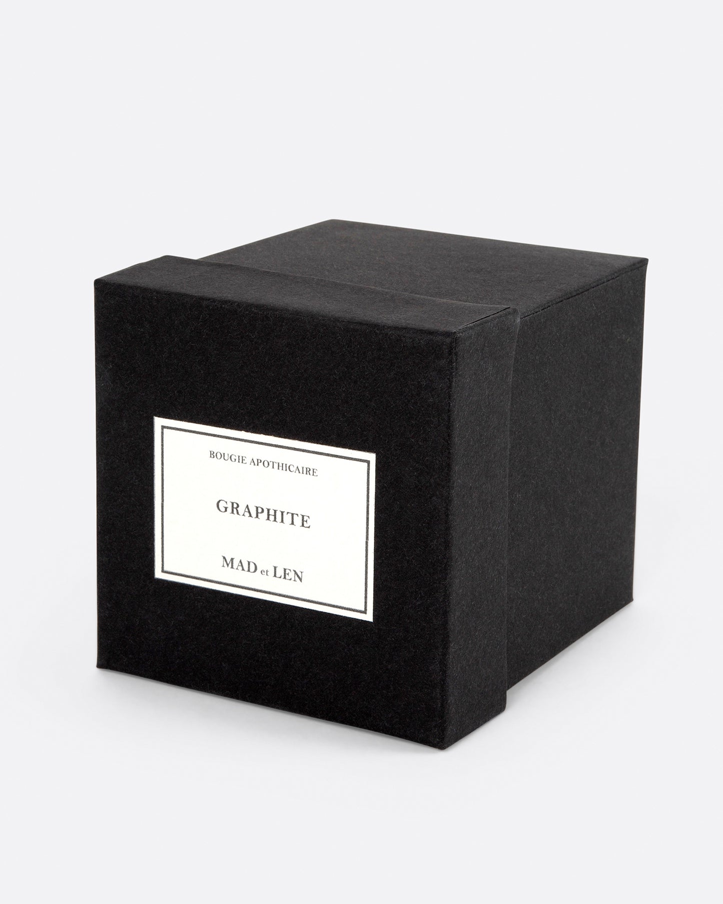 A square black box shown on its side from the top. A label on the top reads: Bougie Apothicaire Graphite Mad et Len.