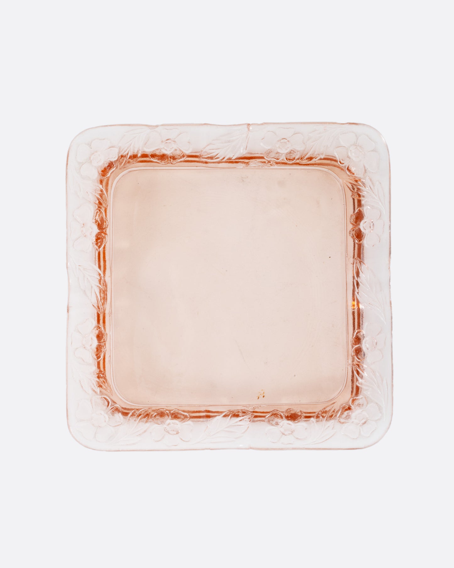 A square pink glass ashtray with a floral design on the edges, shown from the top.