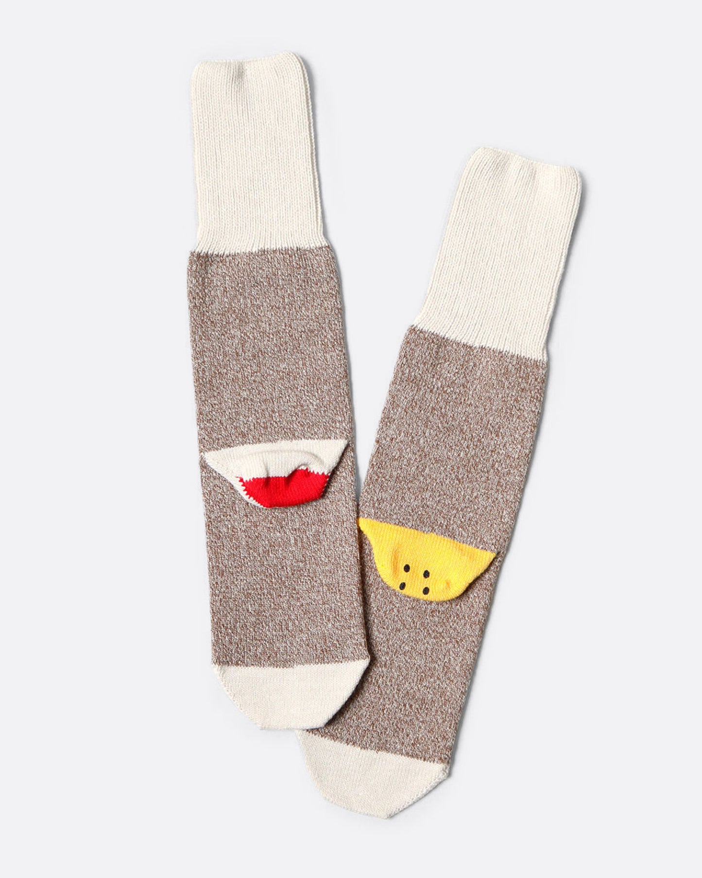 A pair of melange socks with a smiley on one heel and the beginnings of a 'sock monkey' face on the other. Shown from the back.