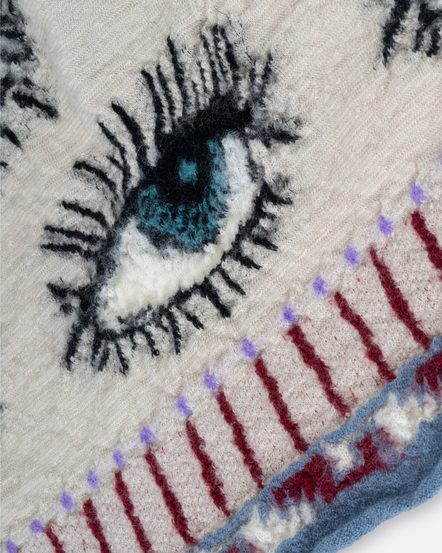 A close up of a cream colored compressed wool blanket from with an all- over eye pattern.
