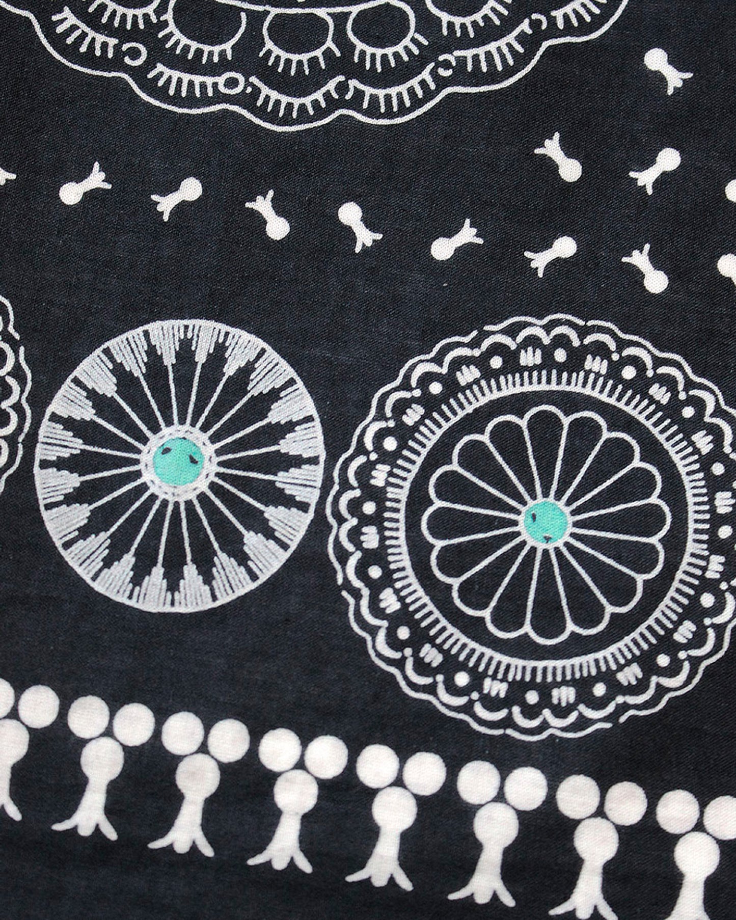A close up of a black selvedge bandana with a pattern of turquoise- centered conchos.