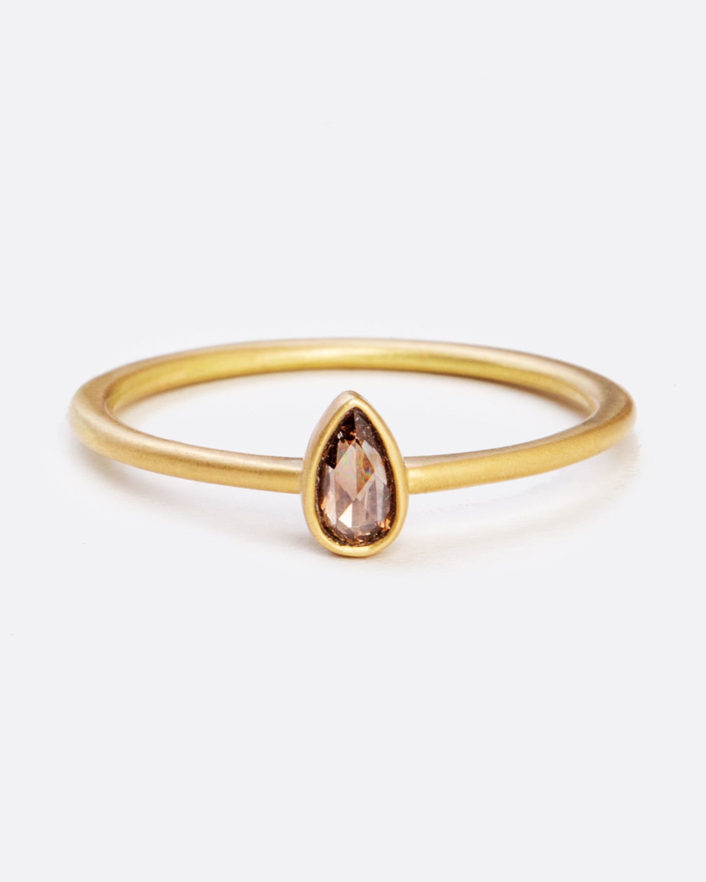 A yellow gold ring with a bezel set teardrop shaped diamond. Shown from the front.