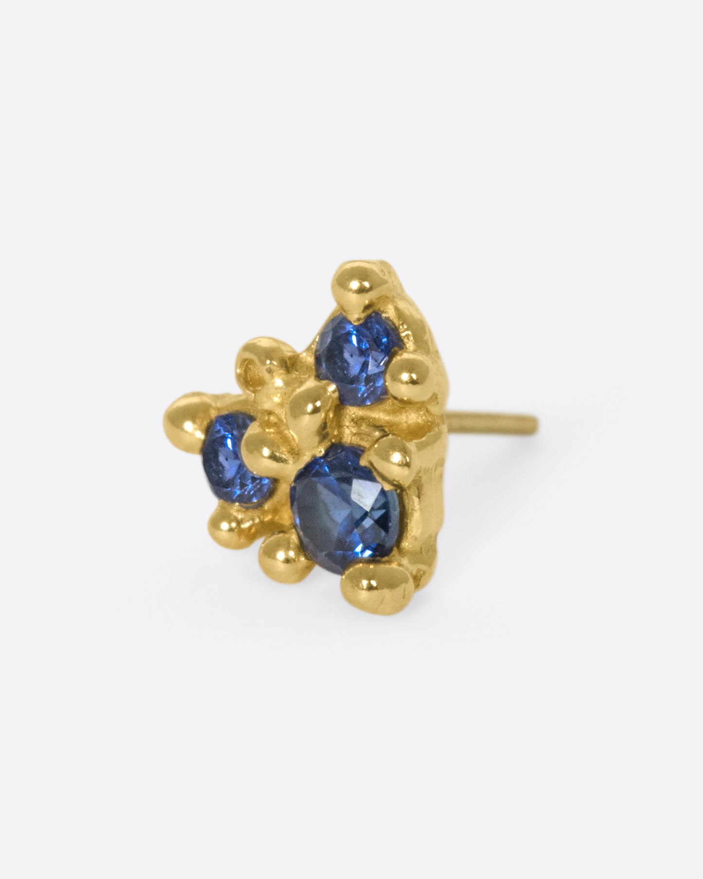 An arrow-like shape with three blue sapphires set in hand formed prongs.