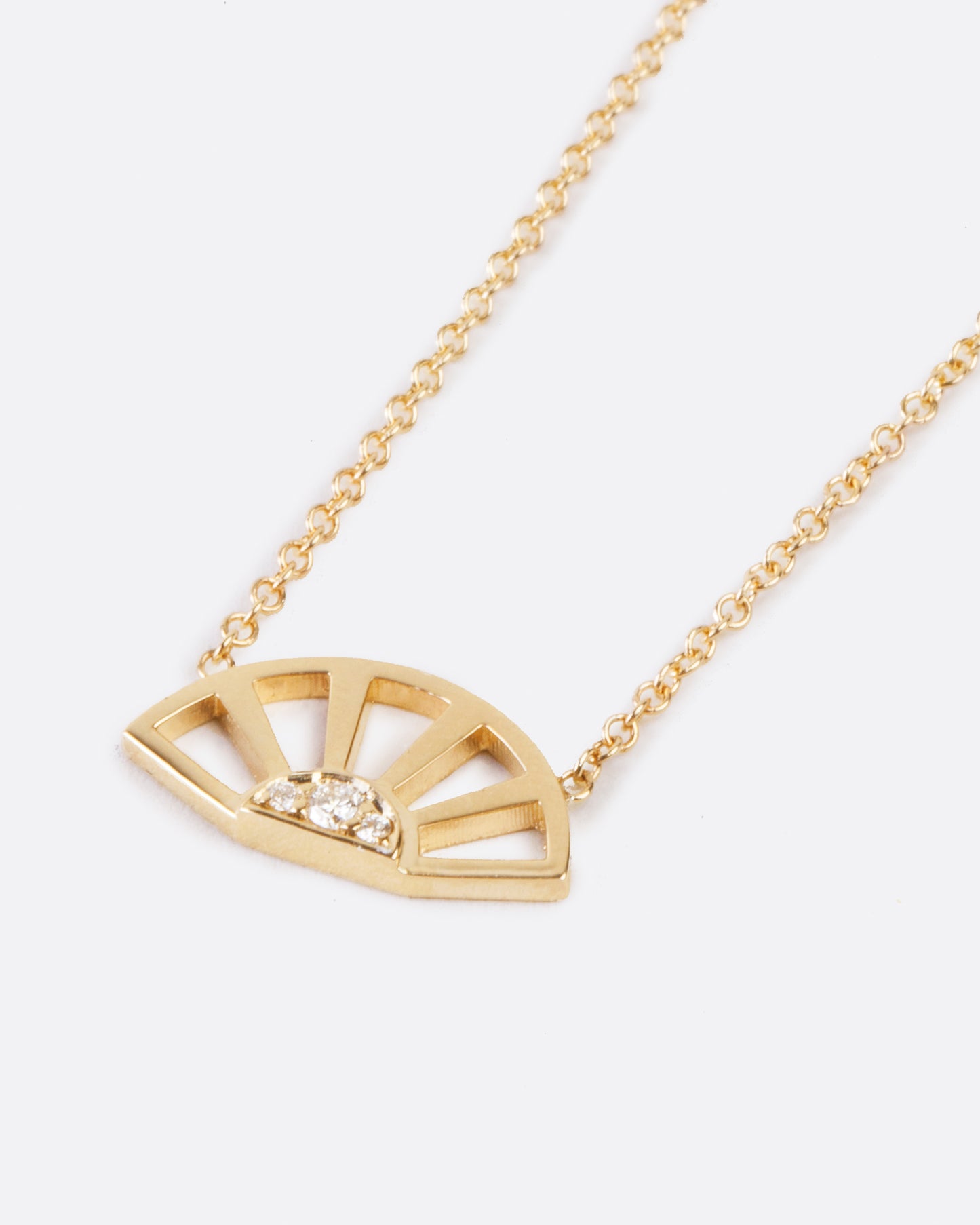 A yellow gold pendant necklace with three white diamonds set at the center of a yellow gold sun and hanging from a yellow gold cable chain. Shown diagonally from the front.