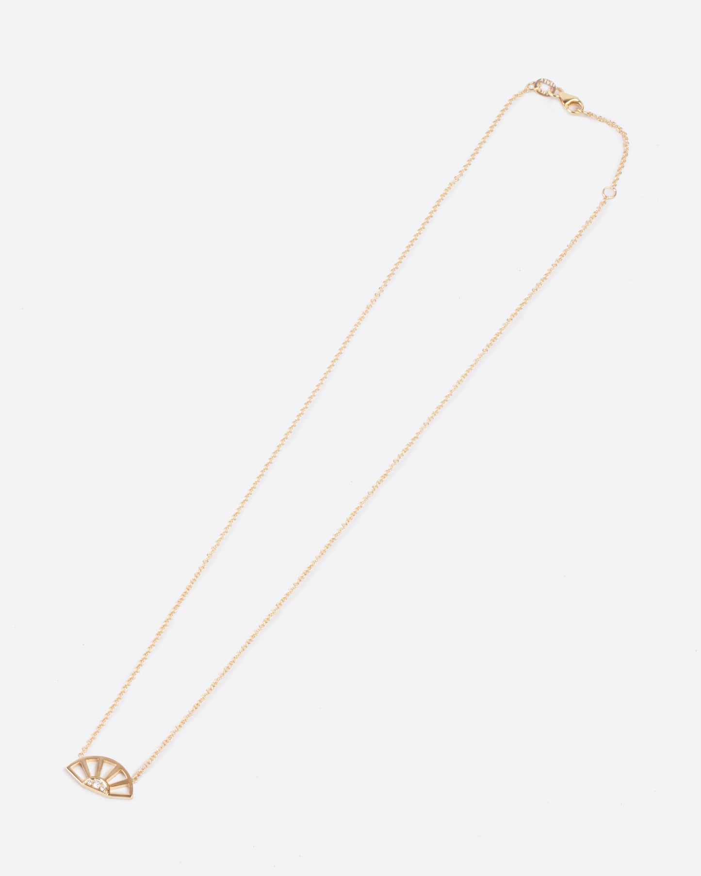 A yellow gold pendant necklace with three white diamonds set at the center of a yellow gold sun and hanging from a yellow gold cable chain. Shown clasped diagonally from the front.