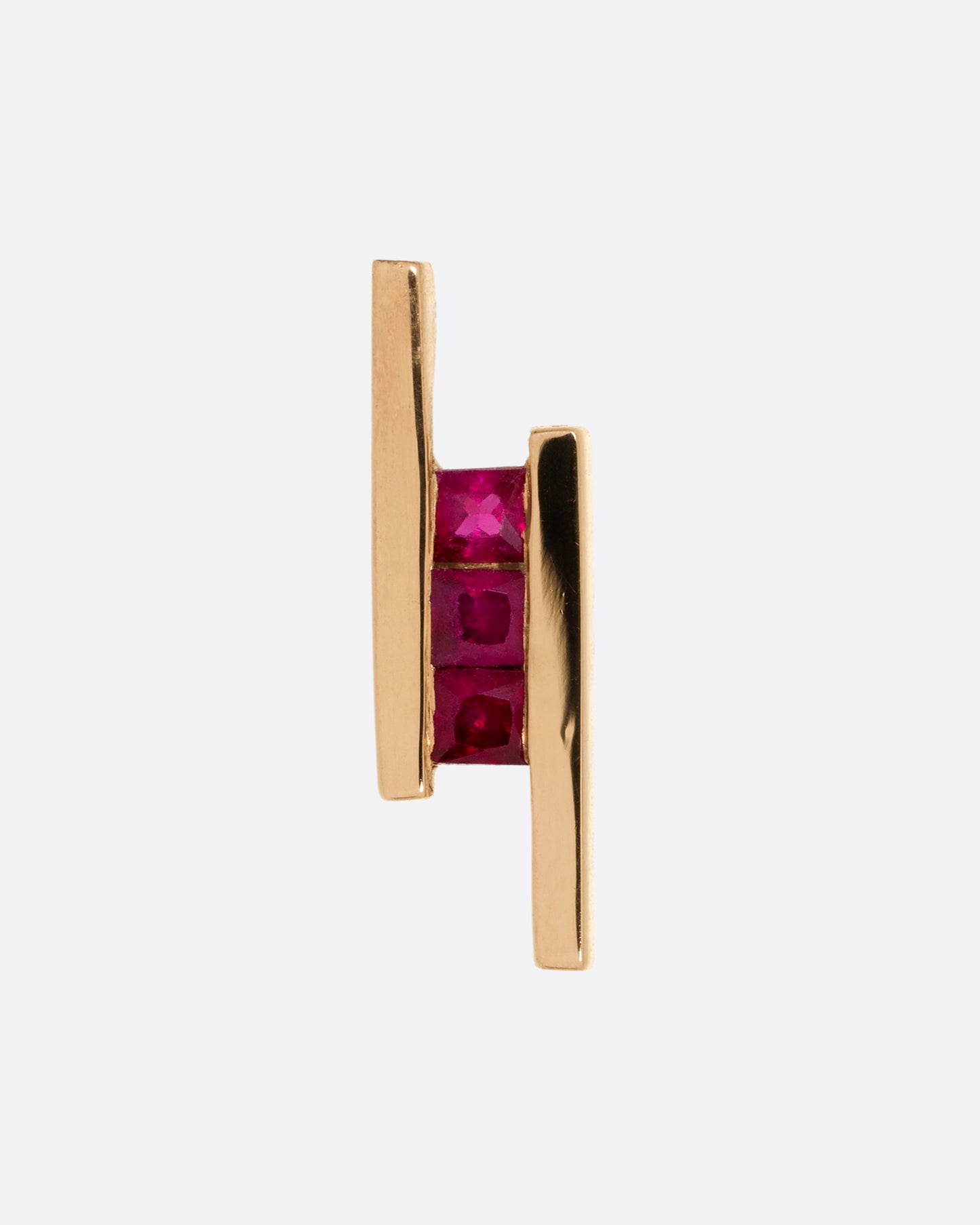 A rose gold stud earring with three rubies between two bars. Shown from the front.