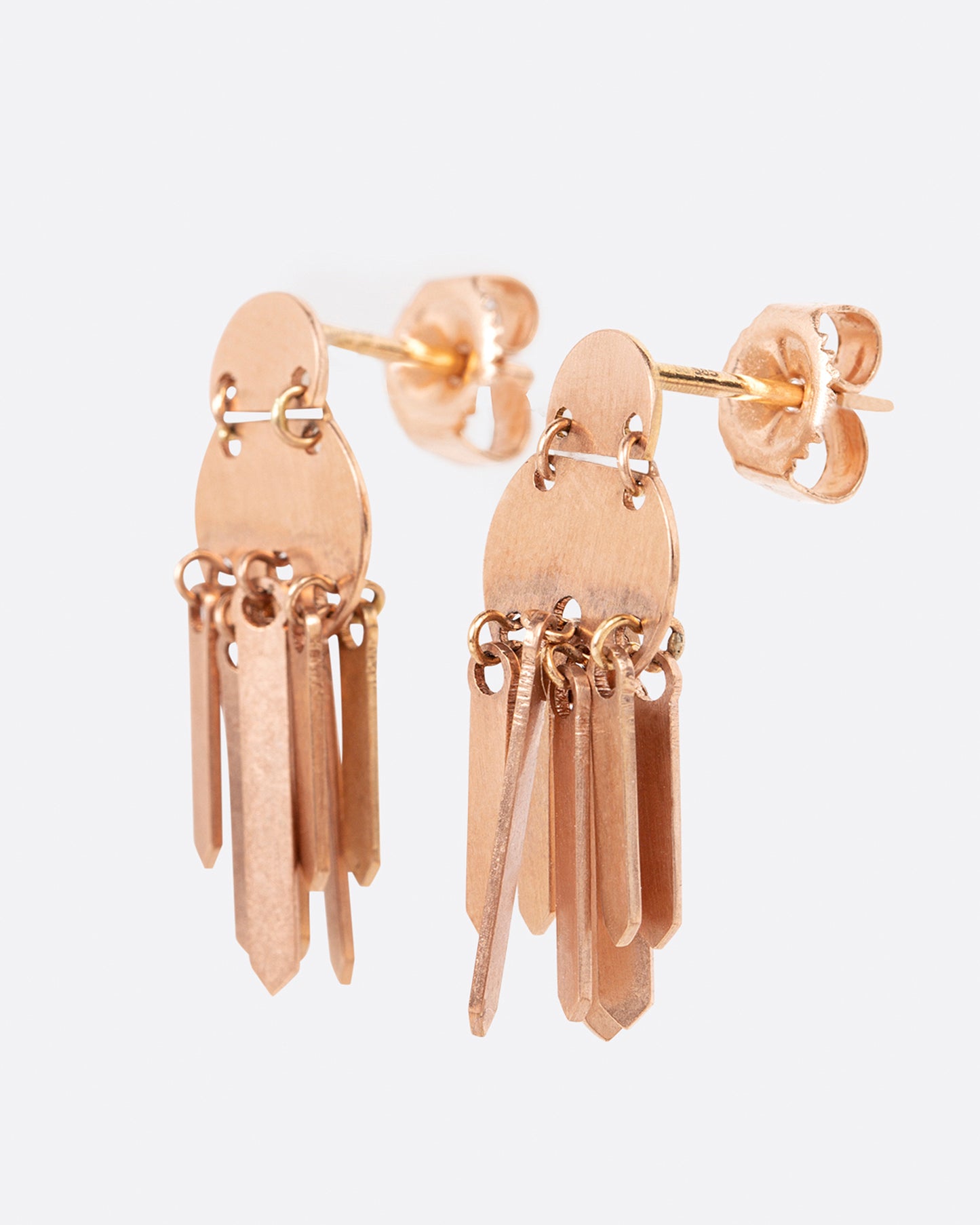 A pair of rose gold fringe earrings with two stacked circular tops. Shown from the side.