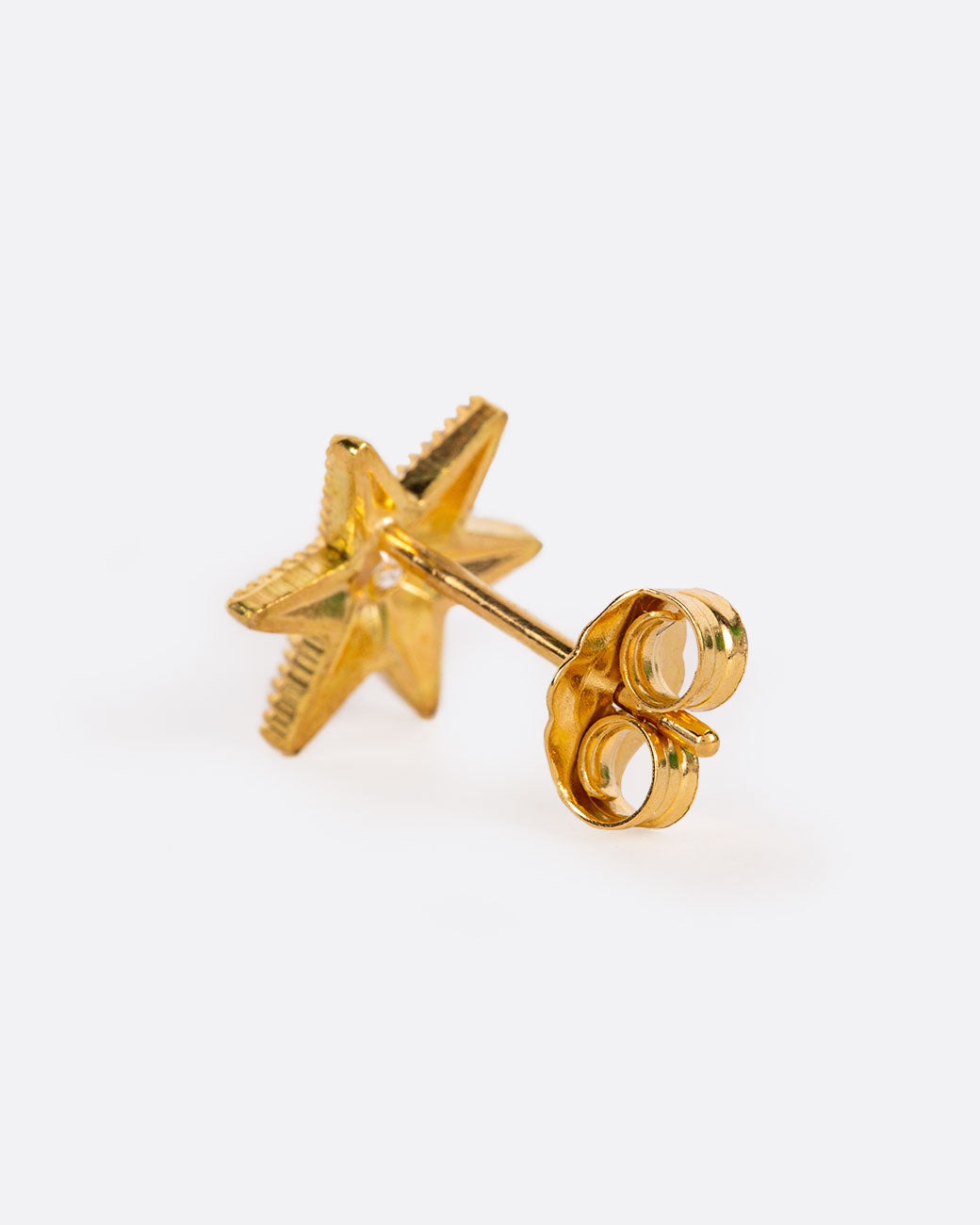A six point star with millgrain texture and a bright white diamond center. Shown from the back.