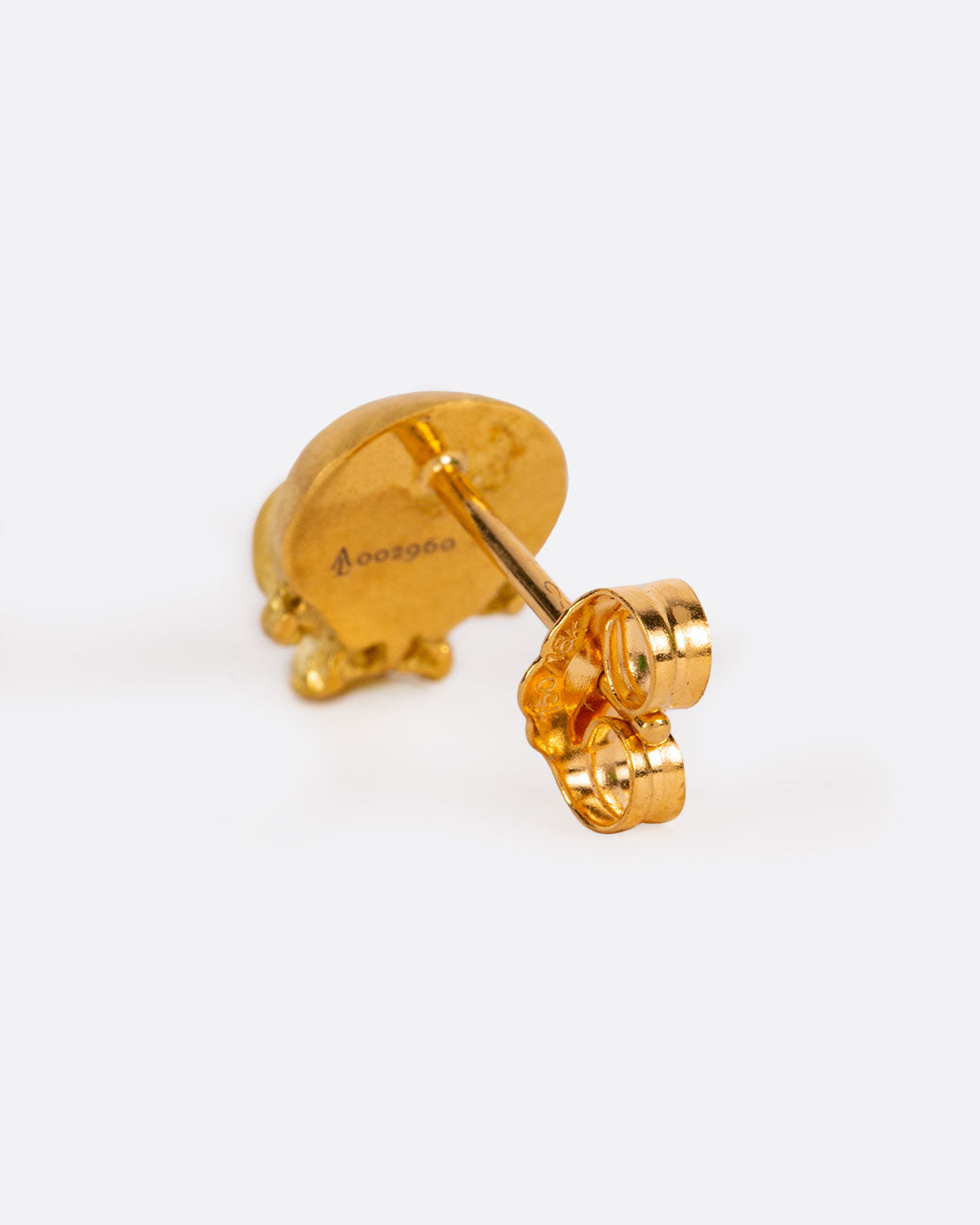 A solid yellow gold skull stud earring. Shown from the back.