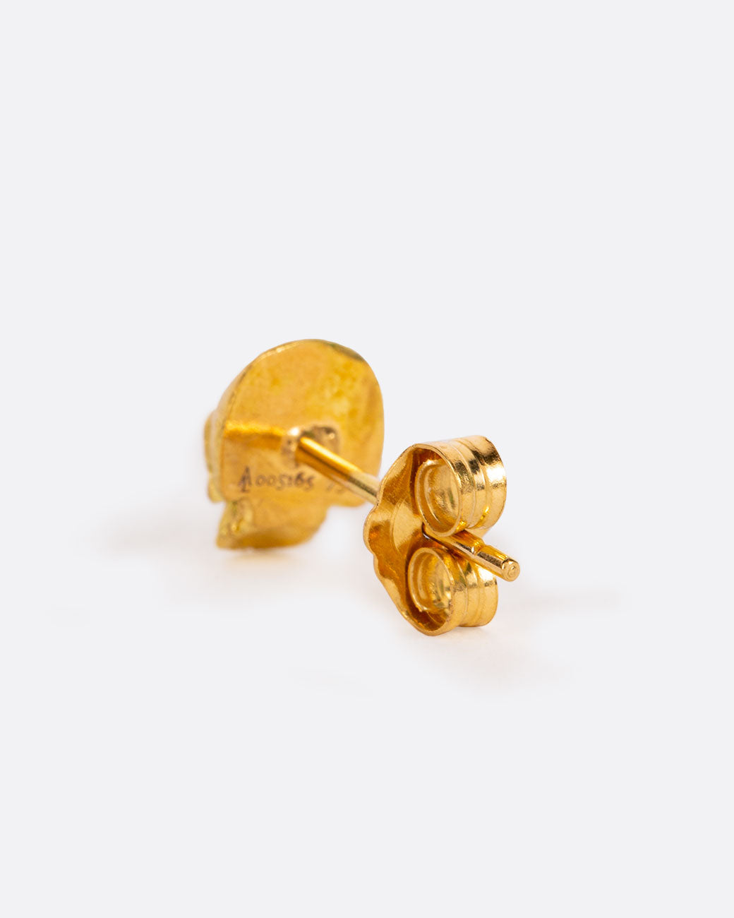 A solid yellow gold skull stud earring. Shown from the back.