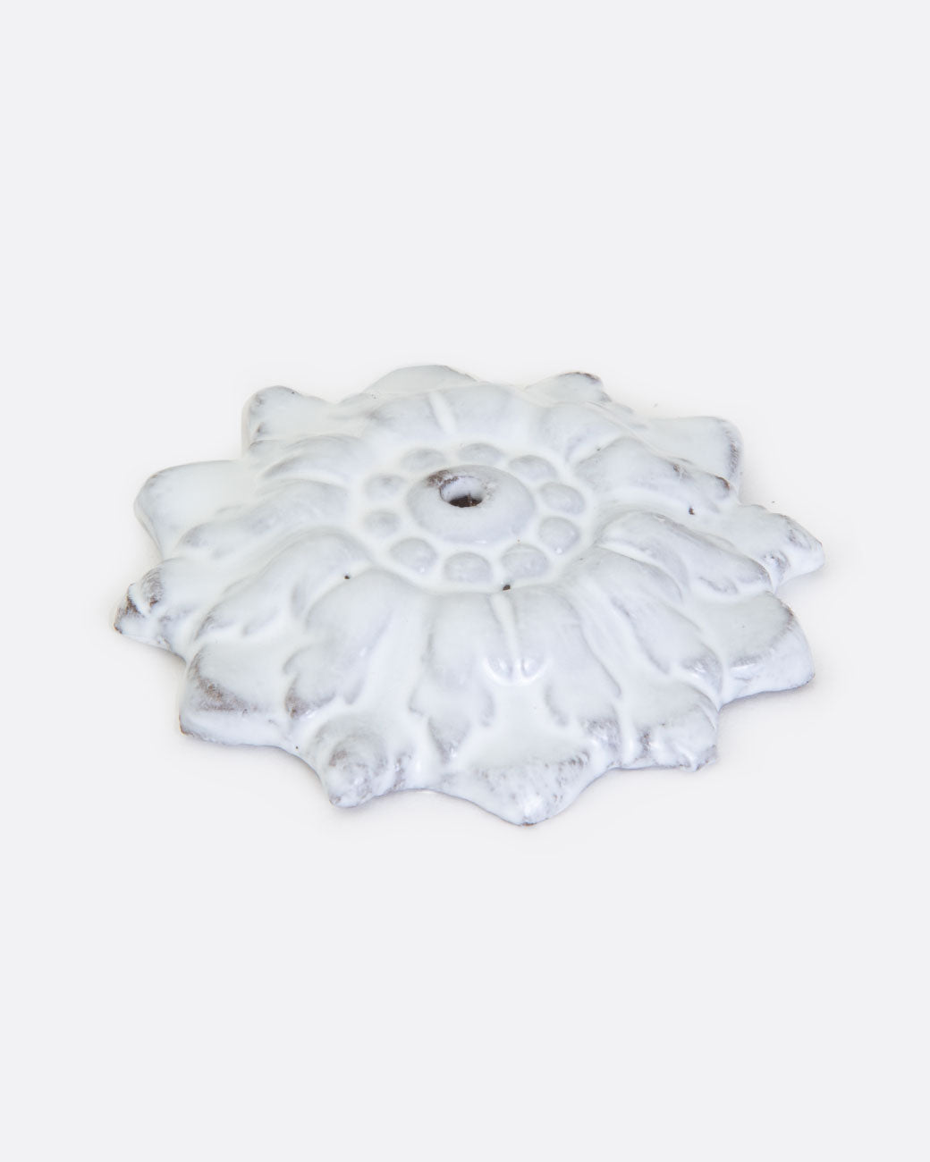 A white ceramic incense holder in the shape of a flower with a center hole. Shown lying flat from the front.