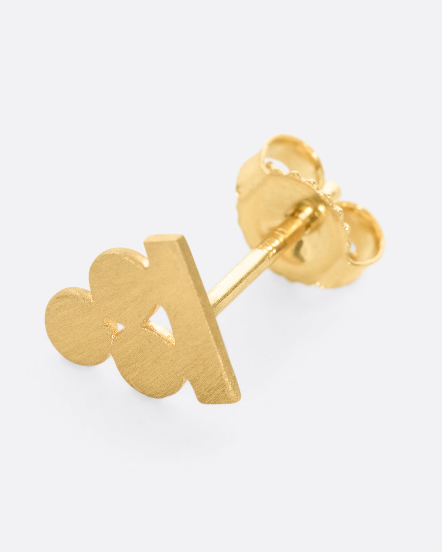 A yellow gold earring with three matte circles sitting on a bar. Shown lying flat from the front.