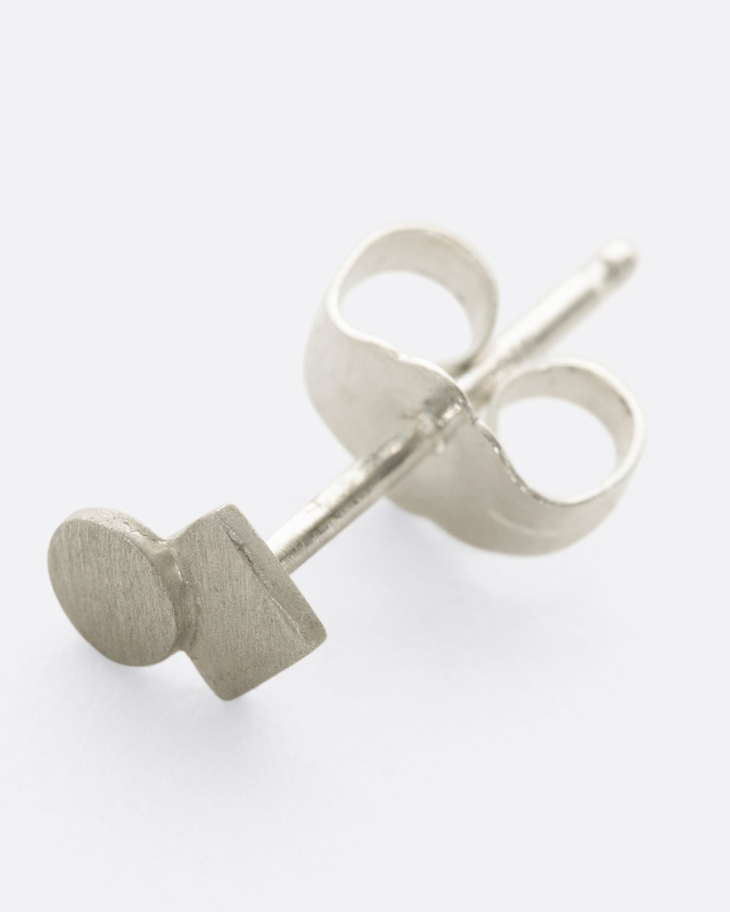 A silver square stud earring with overlapping circle and matte finish. Shown lying flat from the front.