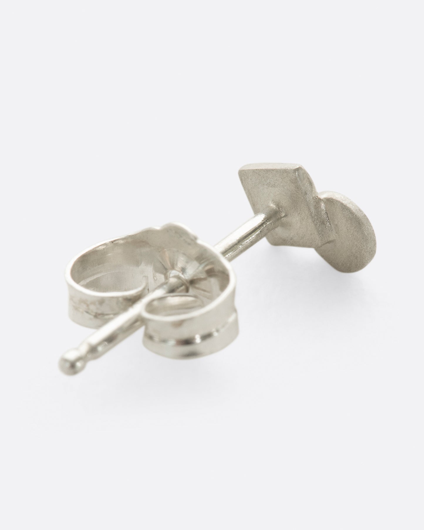 A silver square stud earring with overlapping circle and matte finish. Shown lying flat from the back.