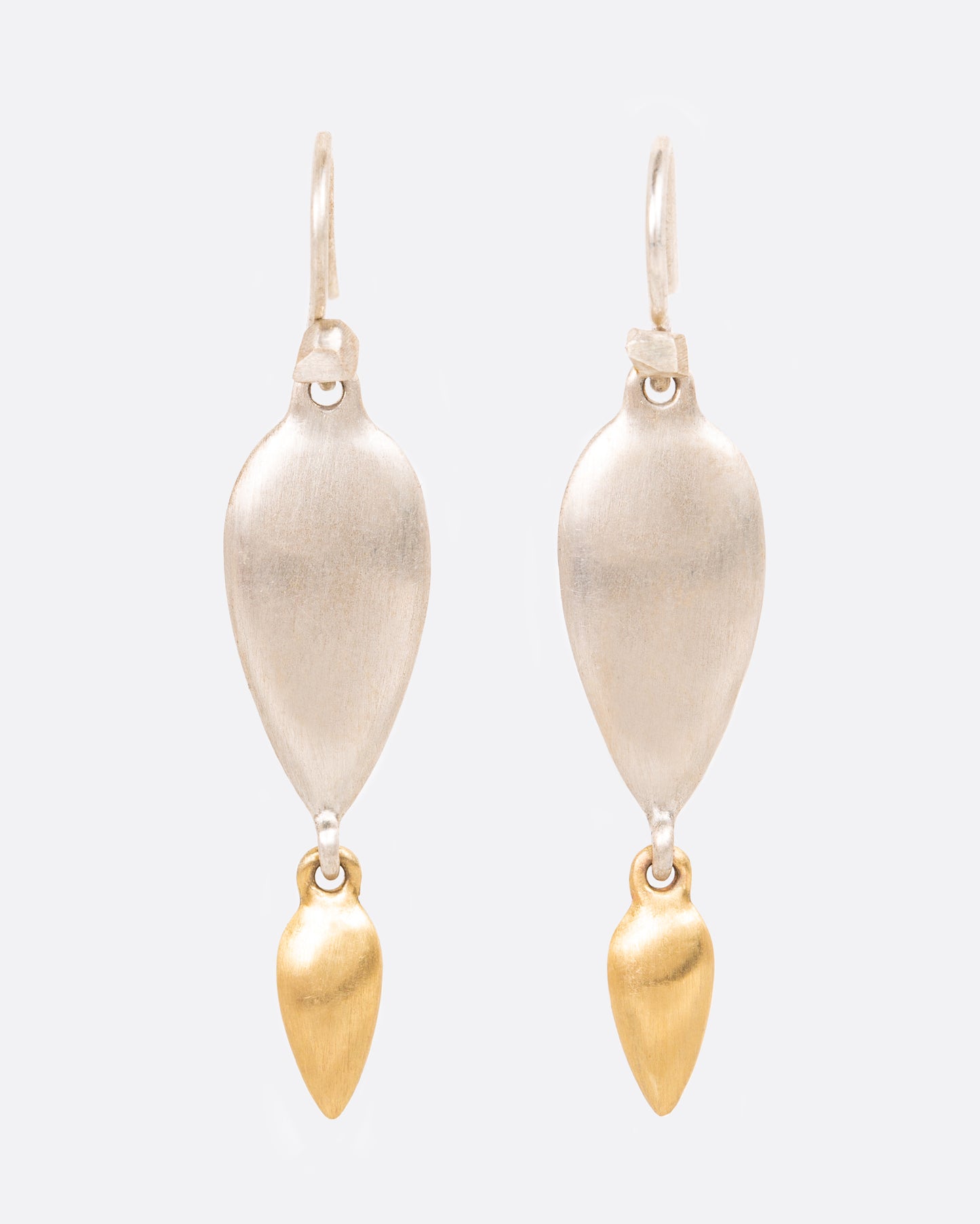 A pair of sterling silver teardrop earrings with yellow gold teardrop dangles at the bottom. Shown from the front.