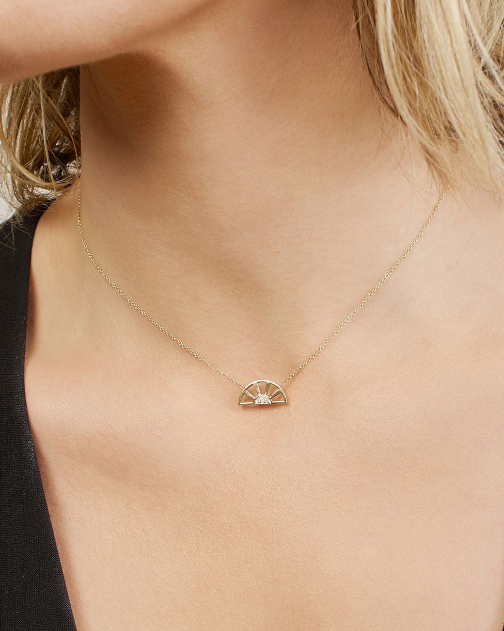 A yellow gold pendant necklace with three white diamonds set at the center of a yellow gold sun and hanging from a yellow gold cable chain. Shown from the front on a person.
