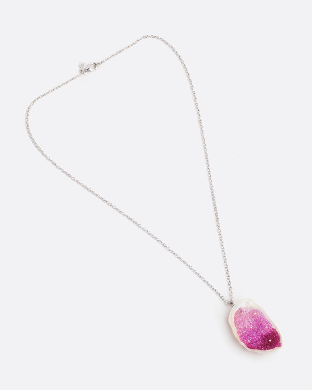 A large freshwater souffle pearl carved out and lined with ombre pink sapphires and seed pearls. It has a pave diamond lined bail and white gold cable chain. Shown from the front lying flat with the clasp closed.