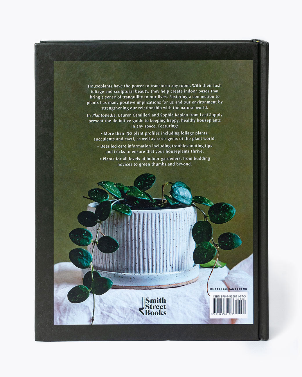 The back cover of the Plantopedia book with a photo of a potted plant and writing in white typeface. Shown standing up.