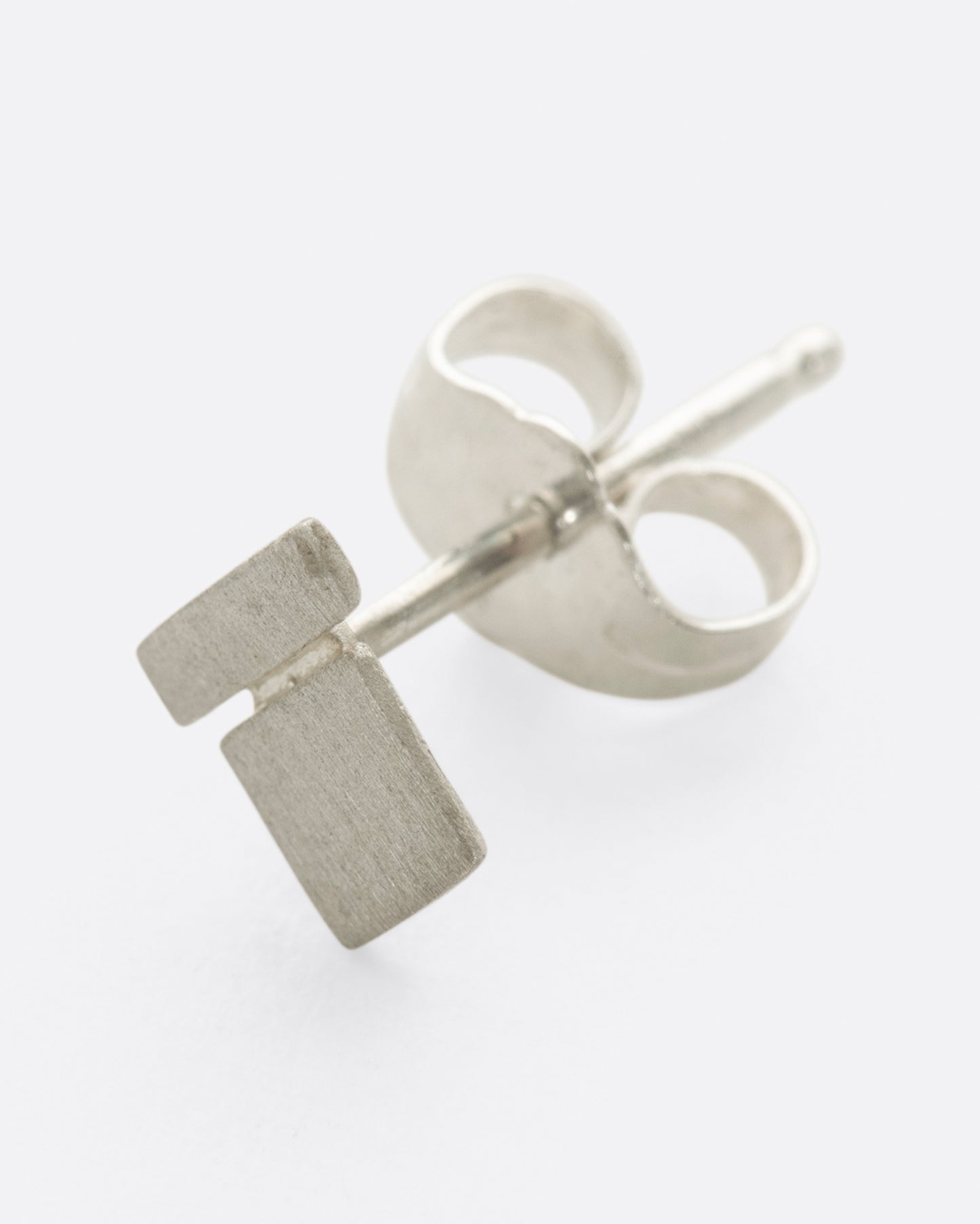 A brushed sterling silver stud earring with two rectangles stacked. Shown at a diagonal tilt from the front.