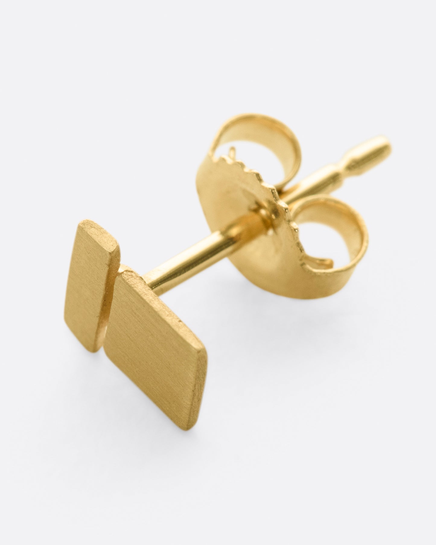 A matte finished yellow gold stud earring with two rectangles stacked. Shown lying flat from the side.