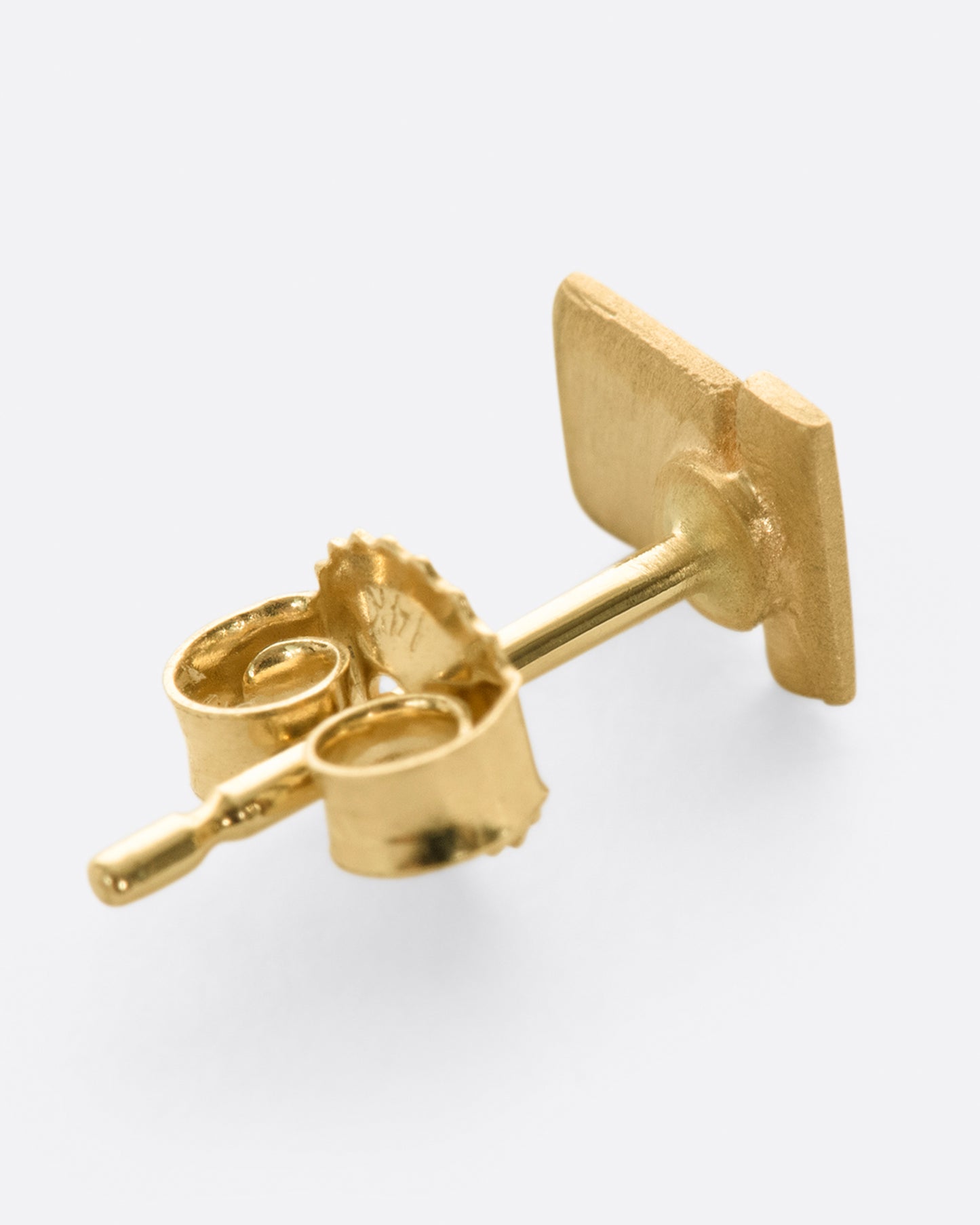 A matte finished yellow gold stud earring with two rectangles stacked. Shown lying flat from the back.