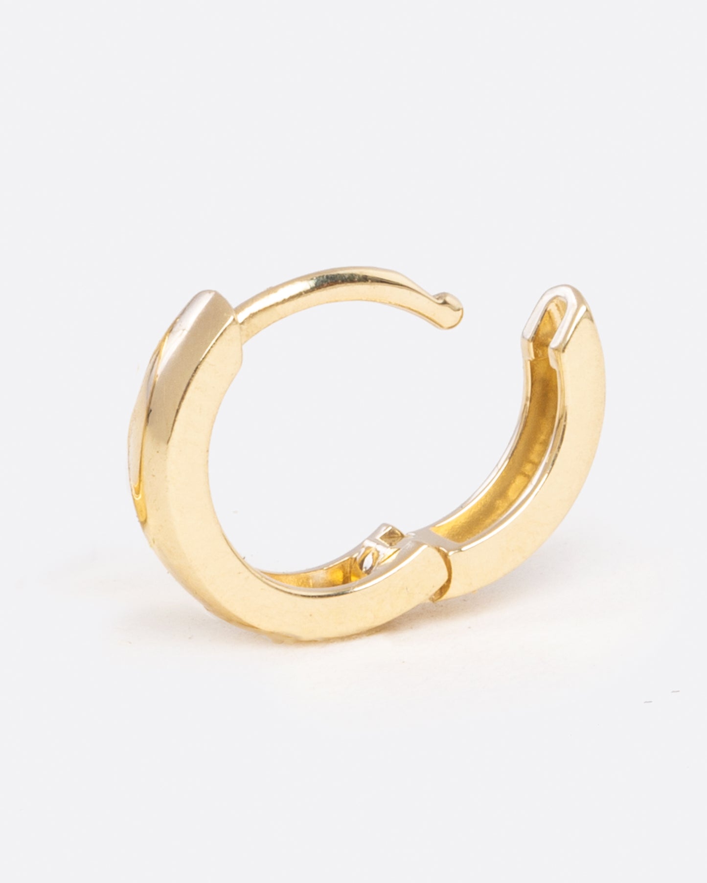 A yellow gold hoop earring with a hinge in the middle. Shown open standing up from the side.