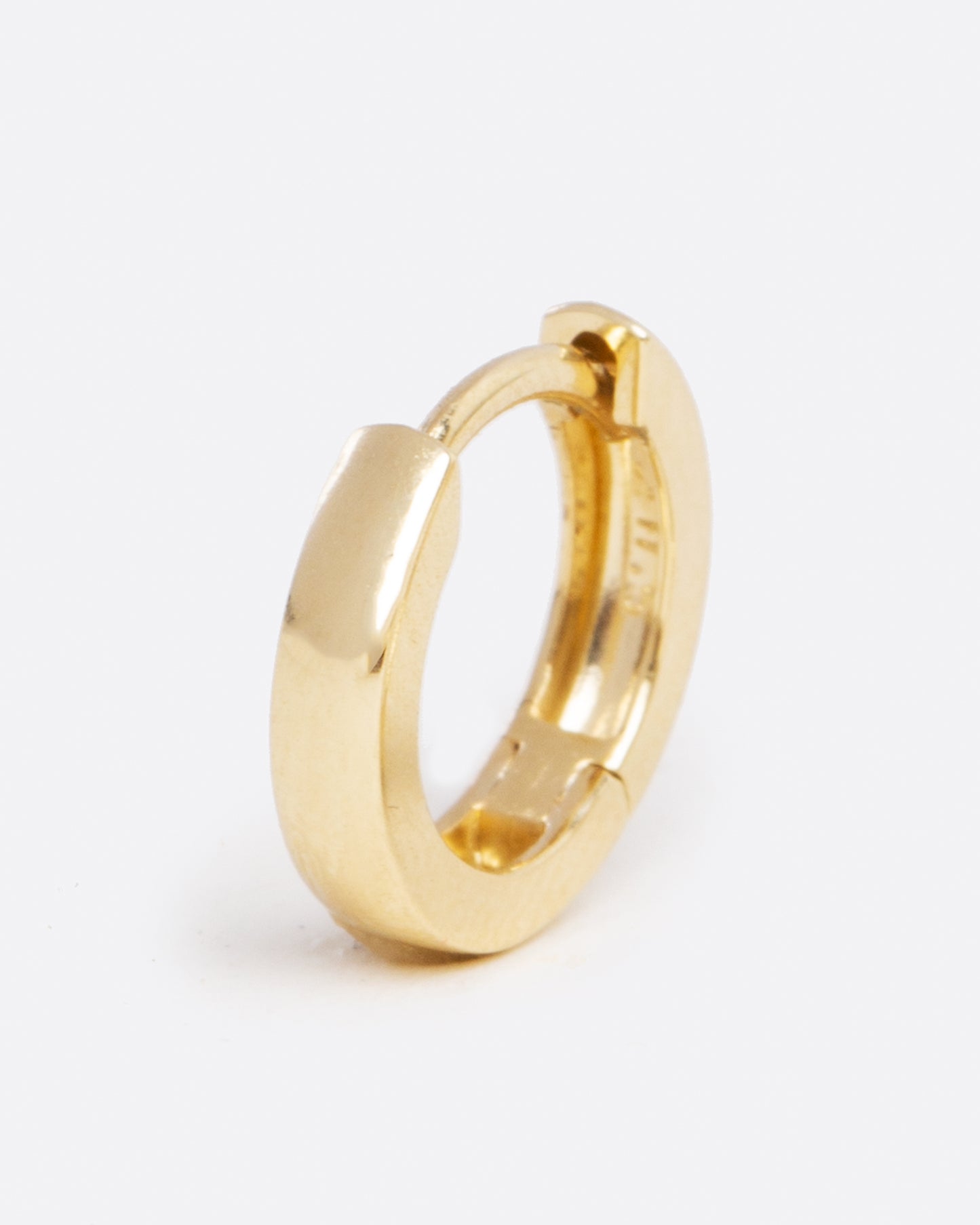 A yellow gold hoop earring with a hinge in the middle. Shown closed standing up from the front.