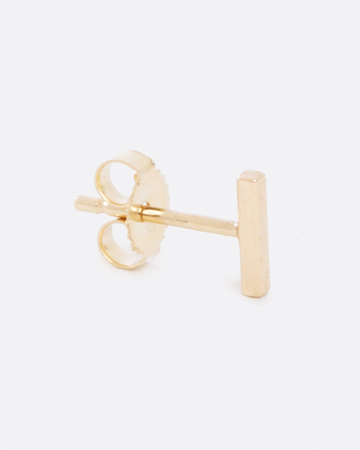 A yellow gold bar earring, shown standing up from the side.