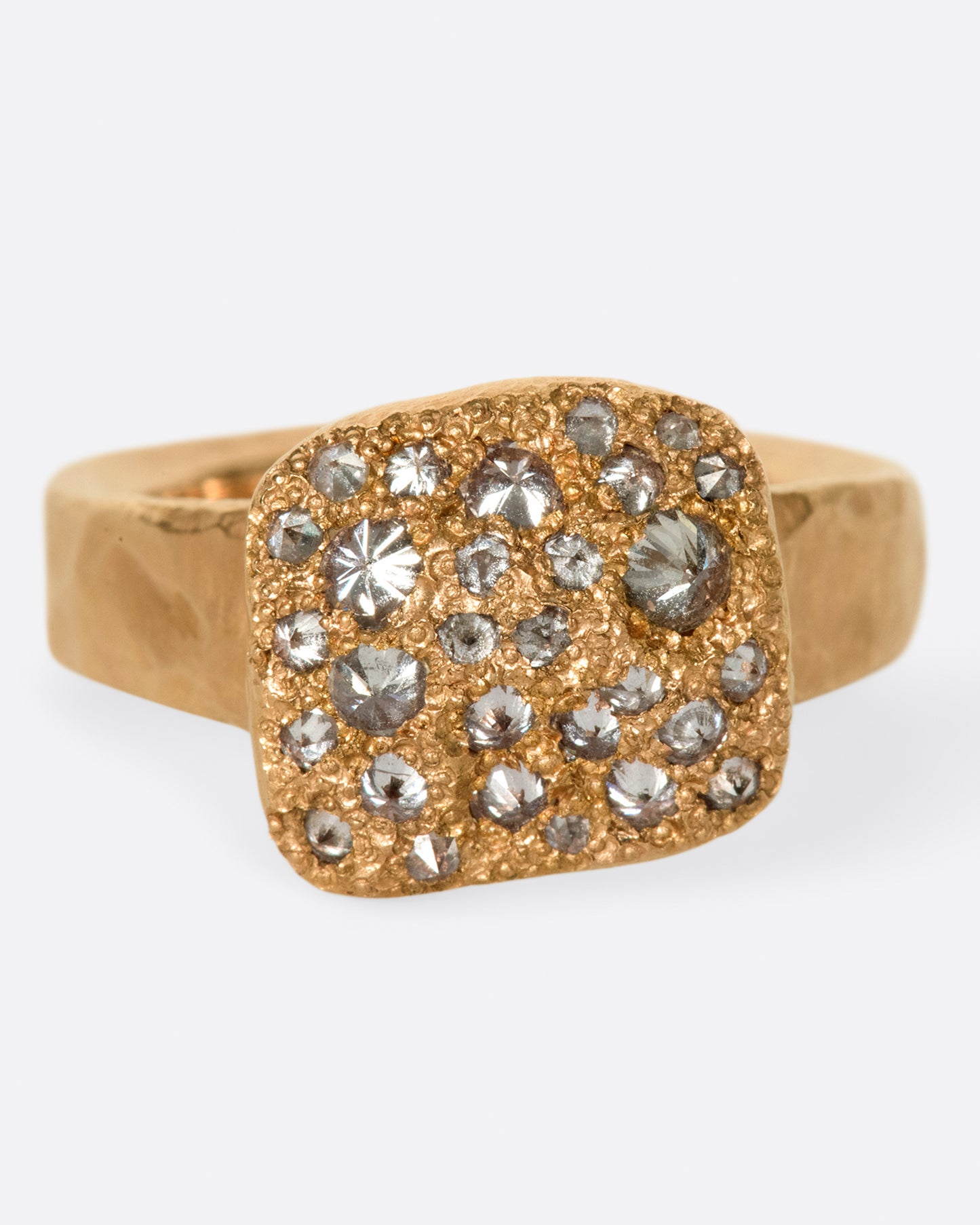 A hammered, hefty rose gold ring with inverted diamonds scattered across its rectangular face. Shown from the front.