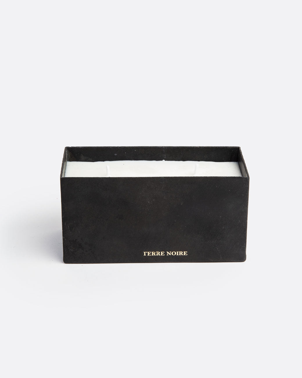 A white block candle with two wicks in a rectangular black container with TERRE NOIRE in gold lettering at the base. Shown from the front.