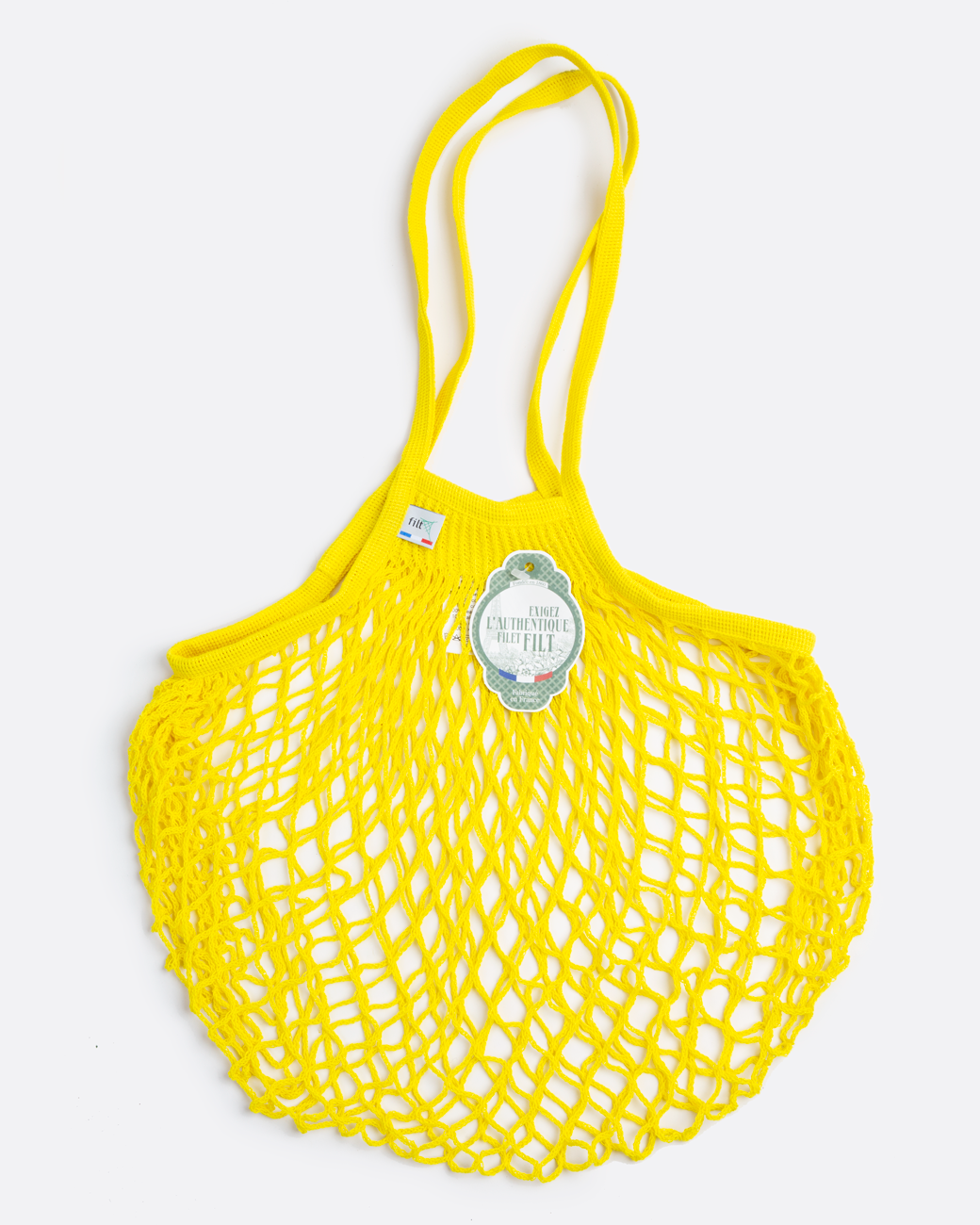 A yellow crochet market bag with a green and white tag. Shown lying flat from the front.