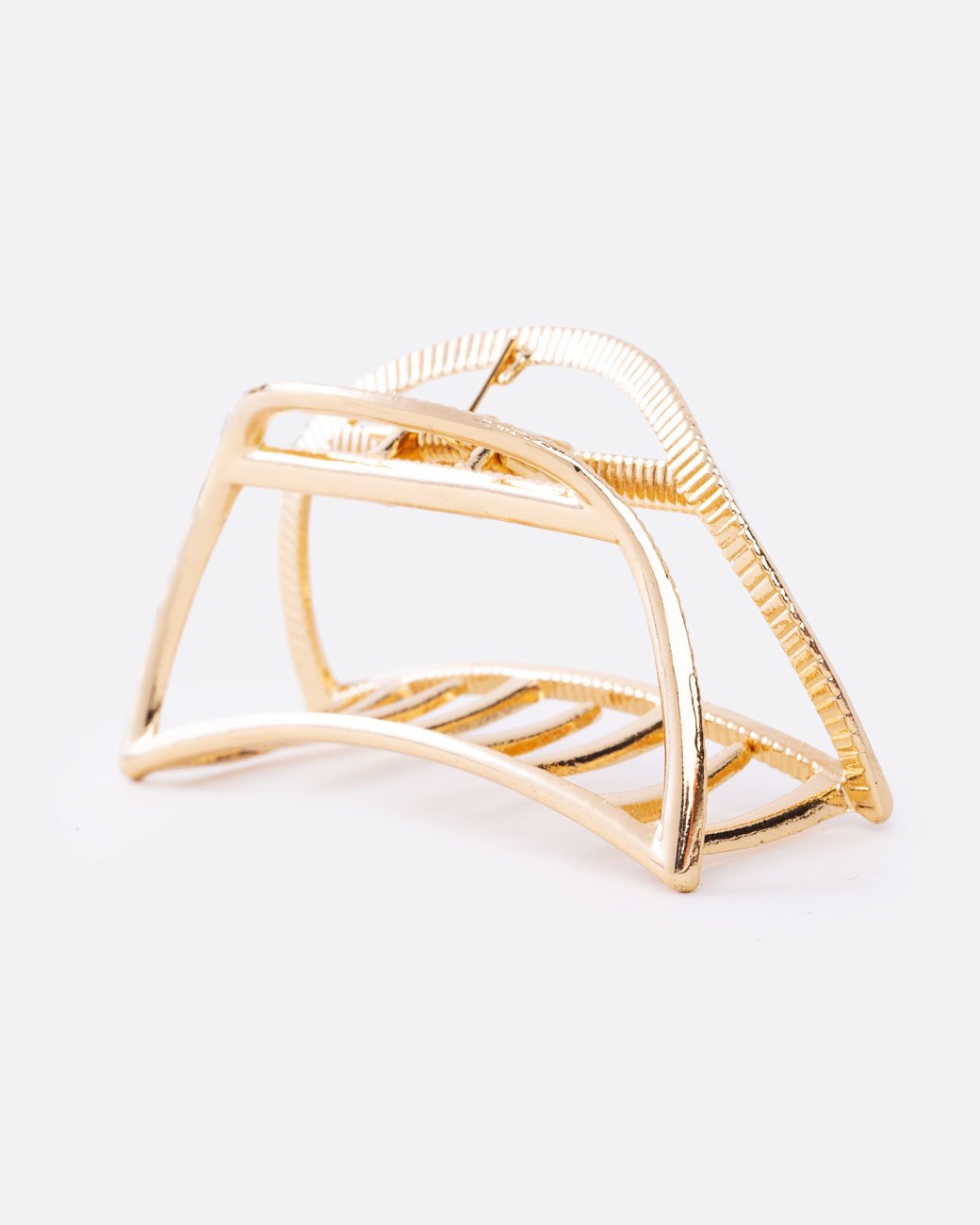 A gold hair clip with a spring loaded top and teeth at the base. Shown at a diagonal from the side.