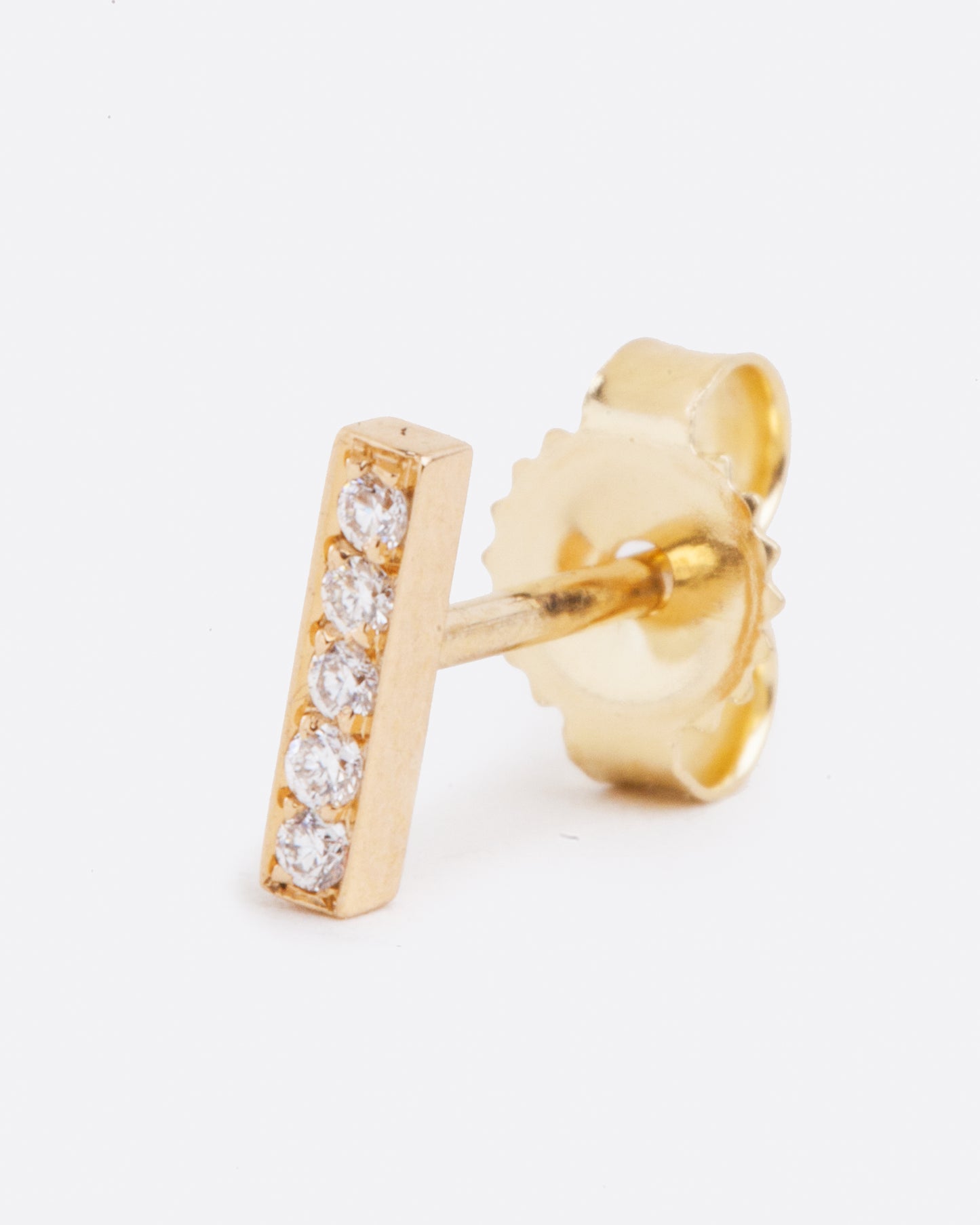 A yellow gold bar stud earring with five white diamonds. Shown standing up from the front.