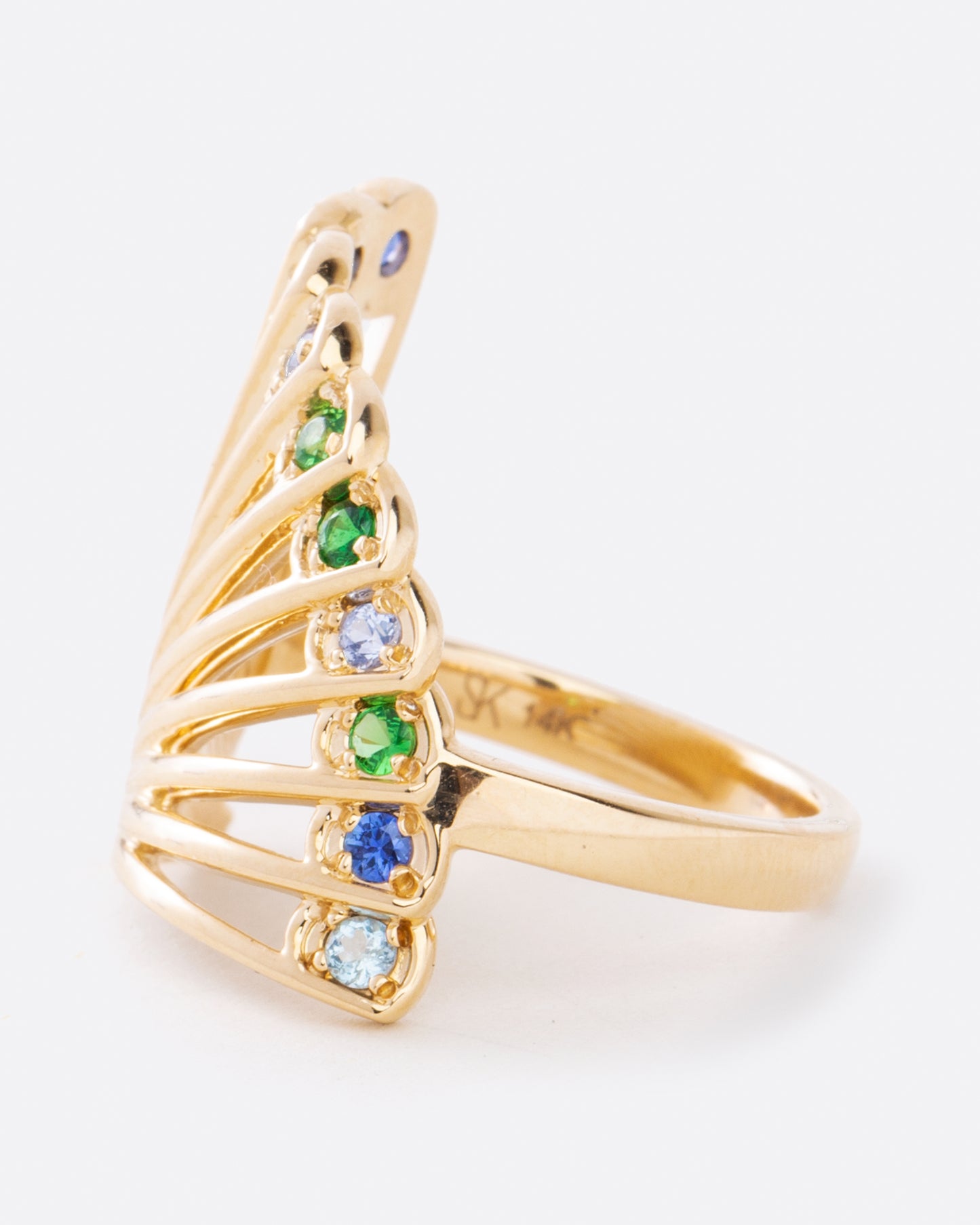 A yellow gold ring in the shape of a fan with multicolor sapphires along the top edge. Shown from the side.