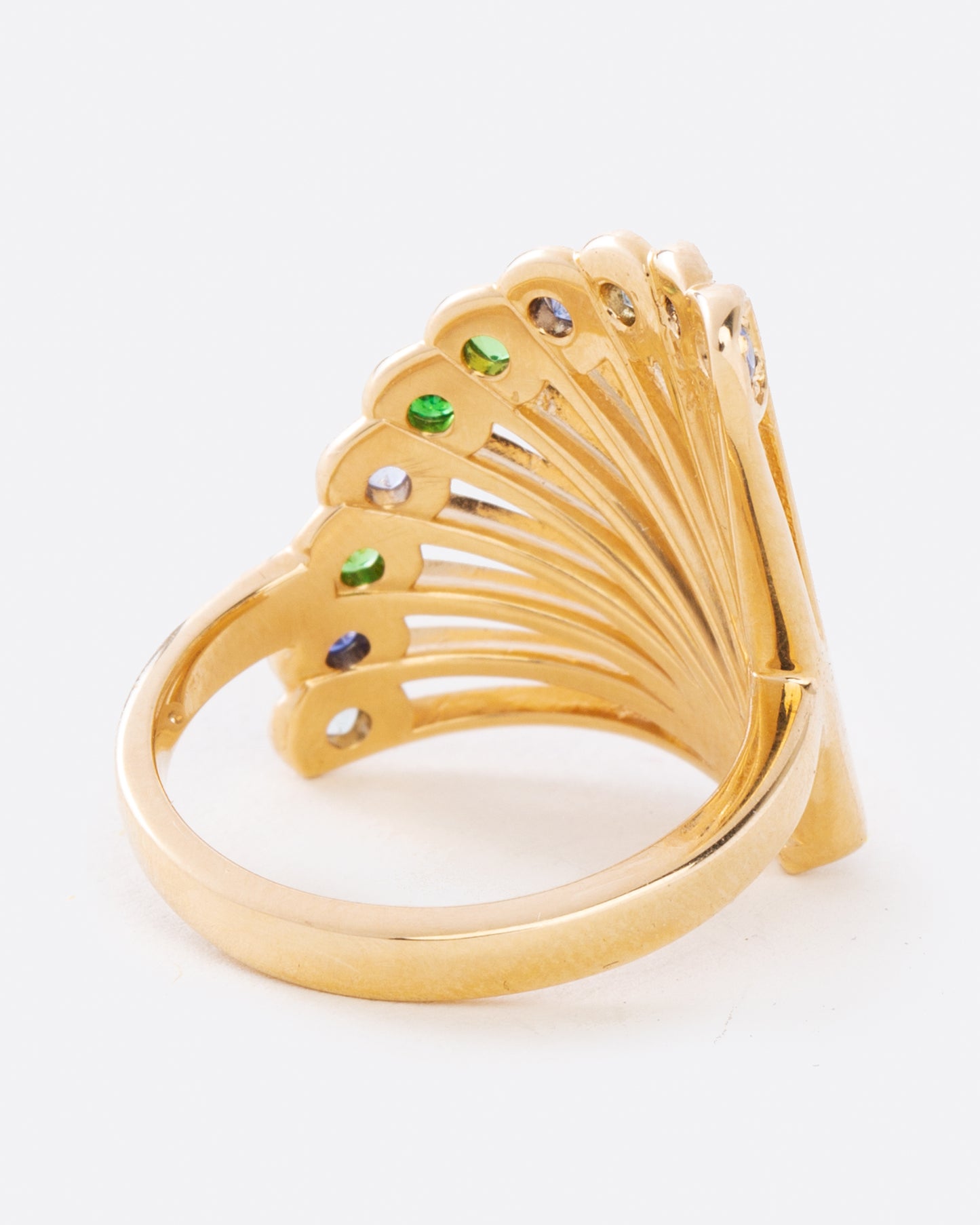 A yellow gold ring in the shape of a fan with multicolor sapphires along the top edge. Shown from the back.