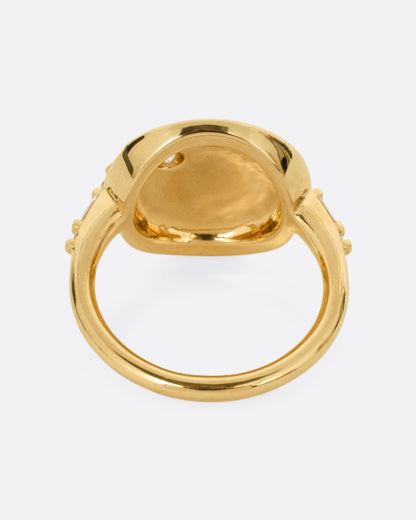 A yellow gold ring with a round face featuring a balance of brilliant round and baguette diamonds. Shown from the back.