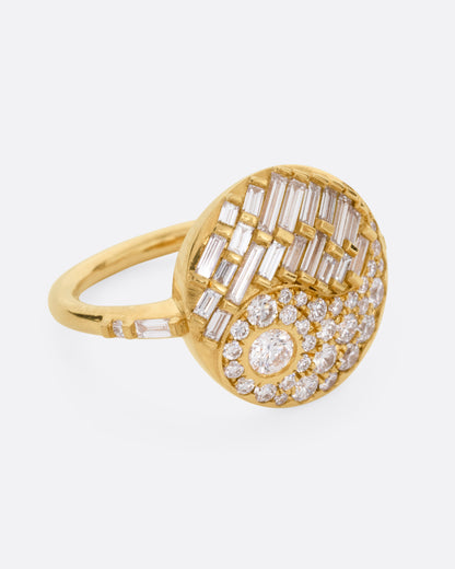 A yellow gold ring with a round face featuring a balance of brilliant round and baguette diamonds. Shown from the side.
