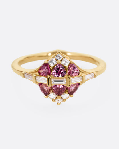 A yellow gold ring with a row of baguette diamonds passing through a cluster of trillion cut garnets and diamond accents. Shown from the front.
