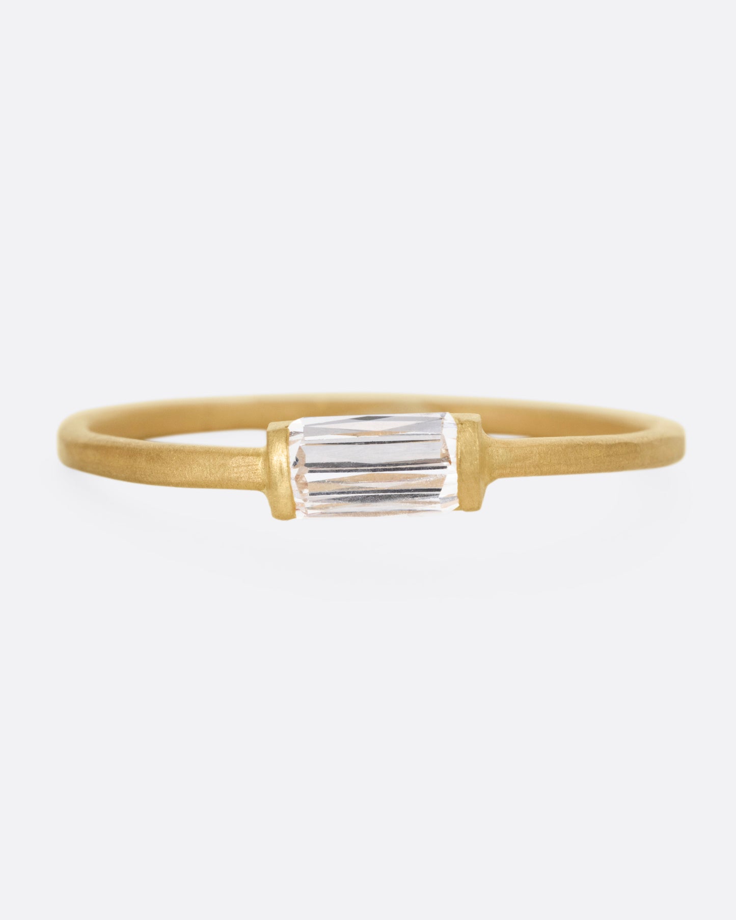 A yellow gold ring with a grey baguette diamond, shown from the front.